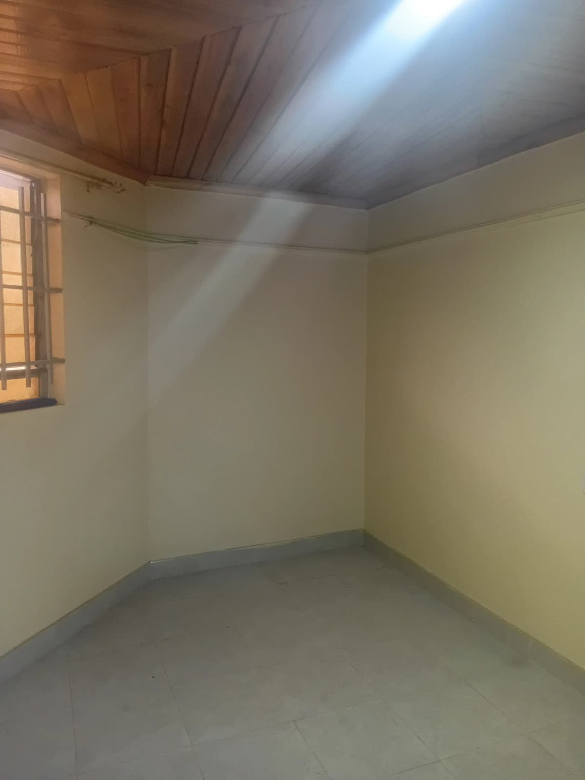 Empty bedroom with wooden ceiling and natural light