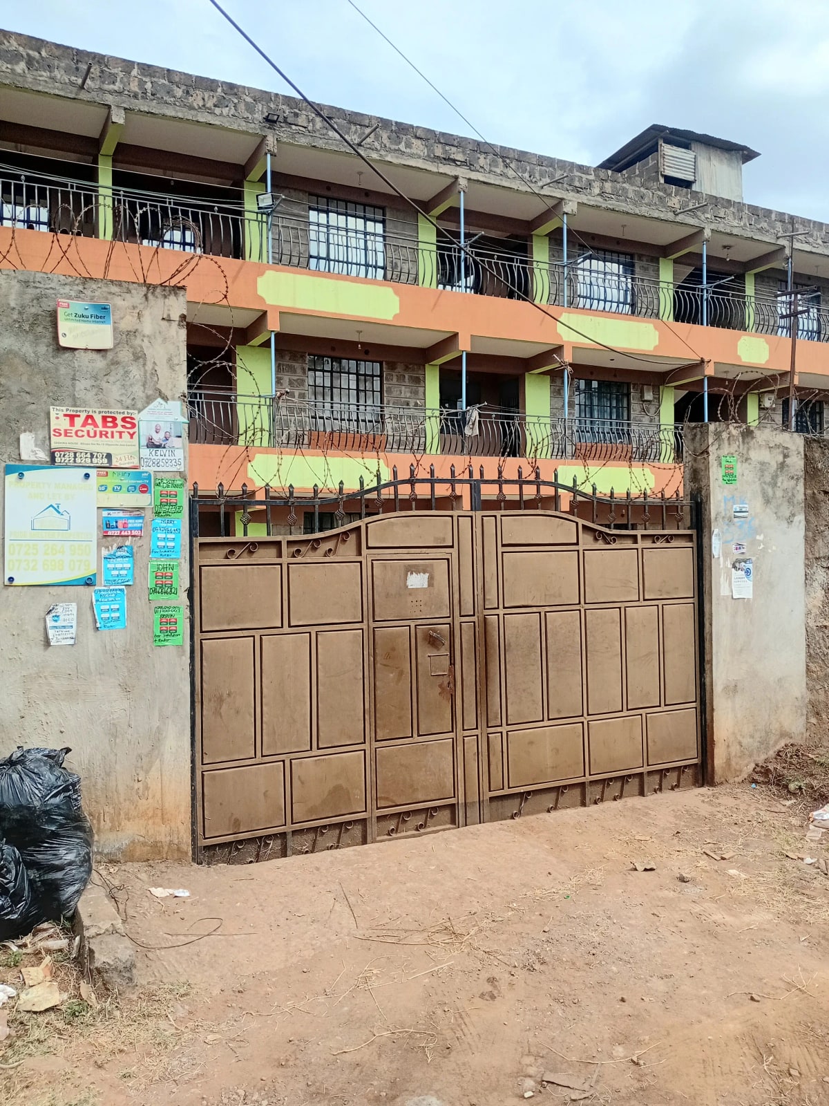 Multi-story residential building with brown metal gate entrance