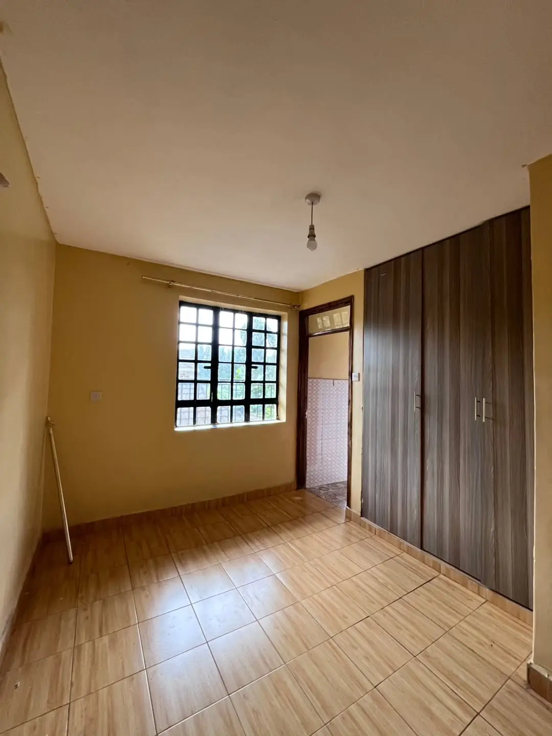 Spacious bedroom with wooden flooring and large window