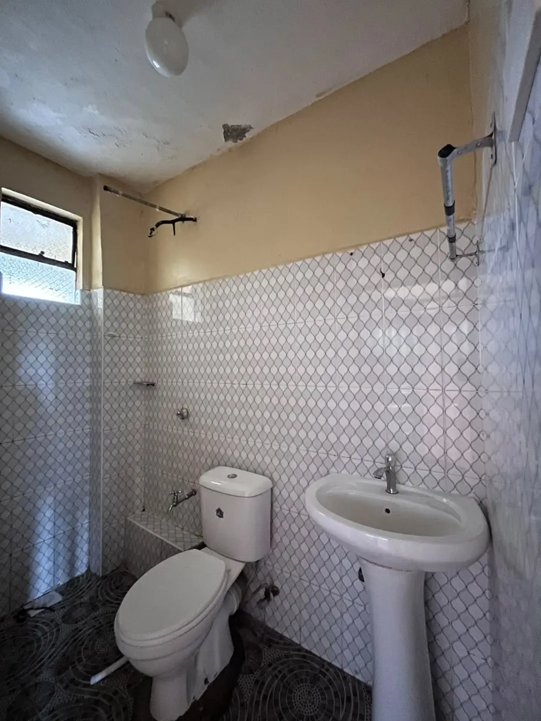 Basic bathroom with toilet, pedestal sink, patterned tiles