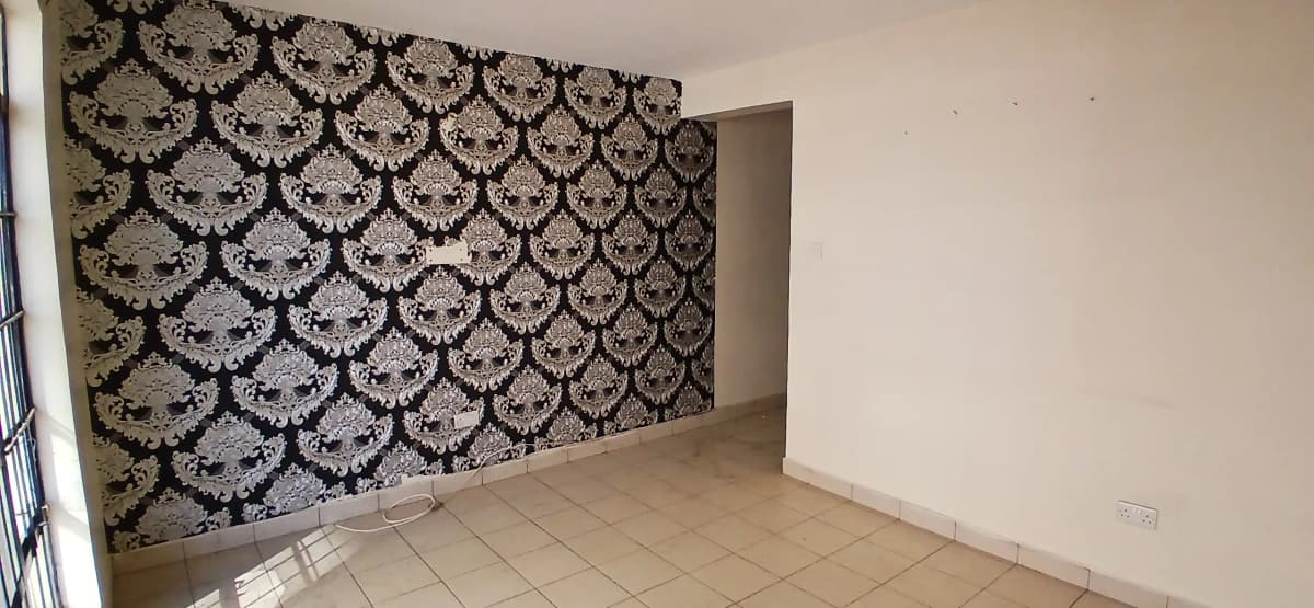 Empty living room with patterned accent wall and tile flooring