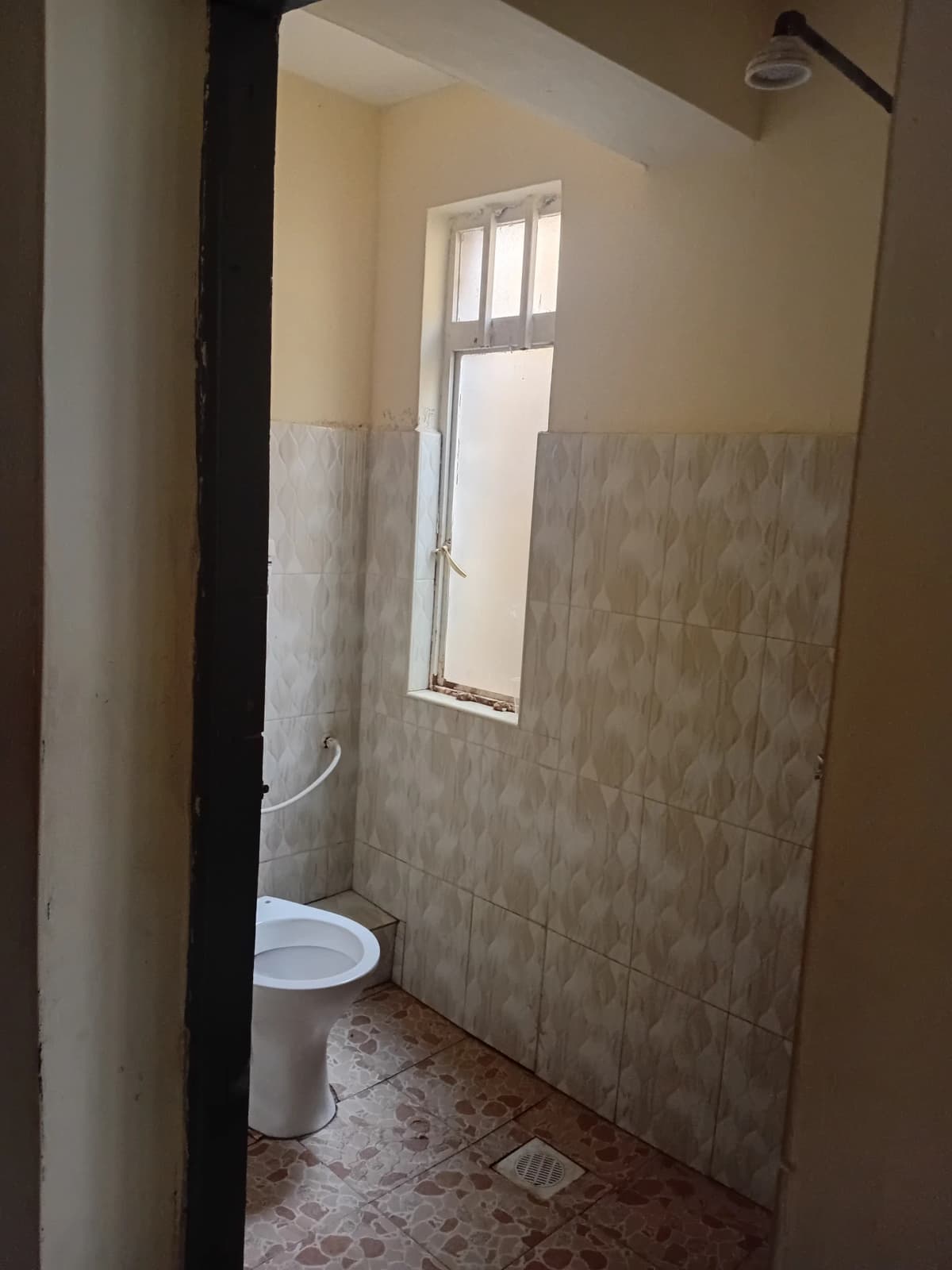 Simple bathroom with toilet, tiled walls, and natural light