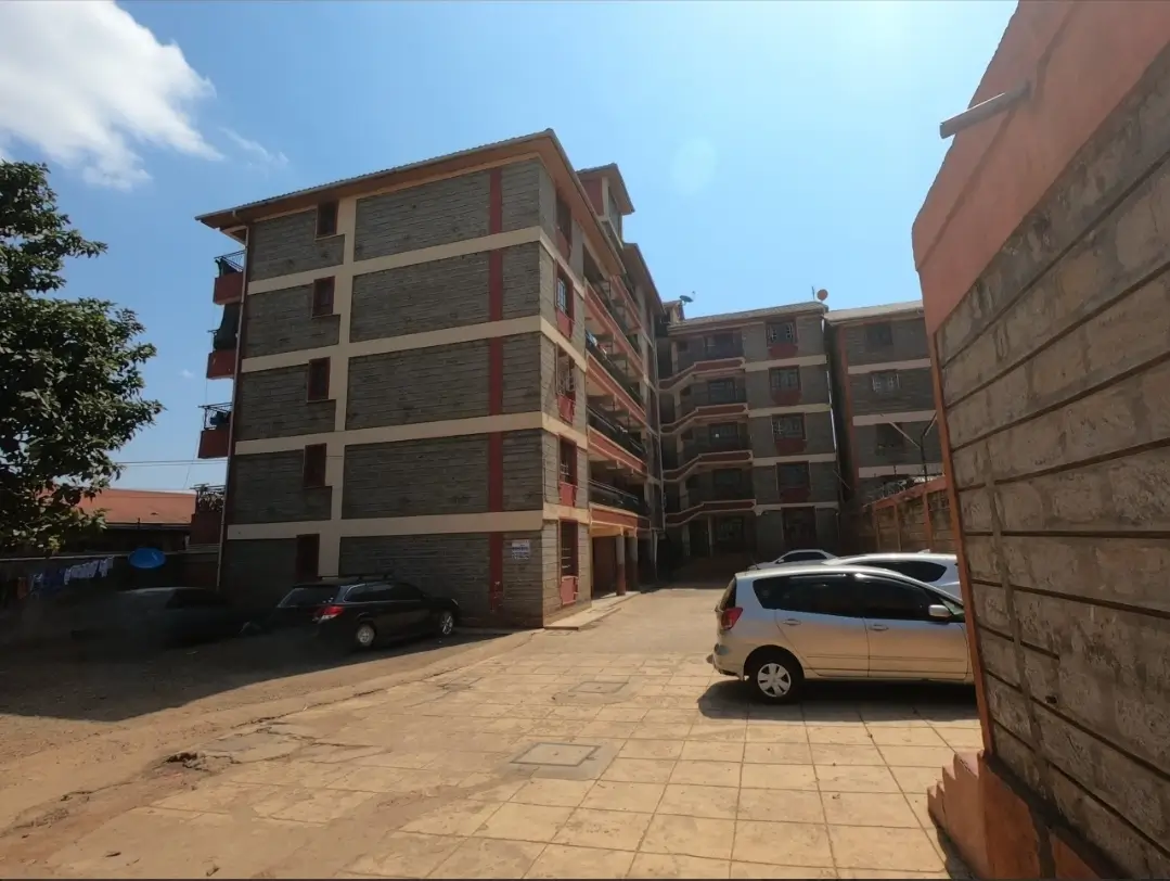 Multi-story residential building with paved compound parking area