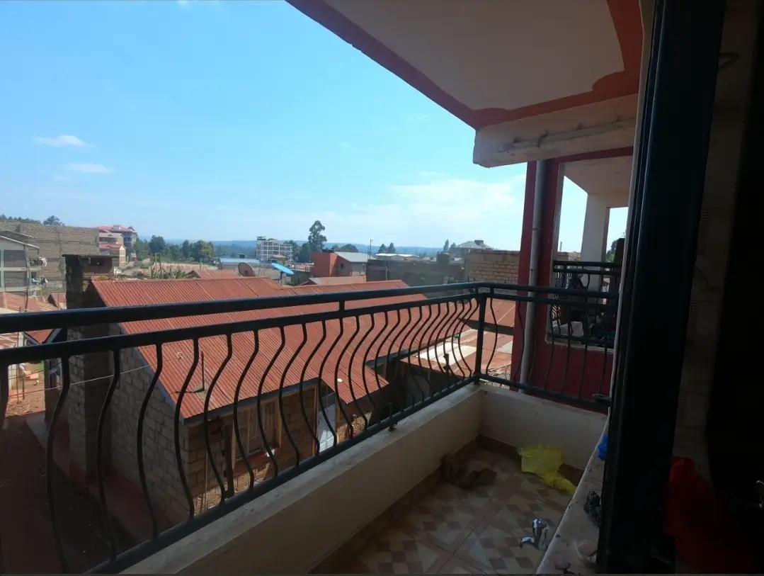 Spacious balcony with metal railing overlooking residential landscape