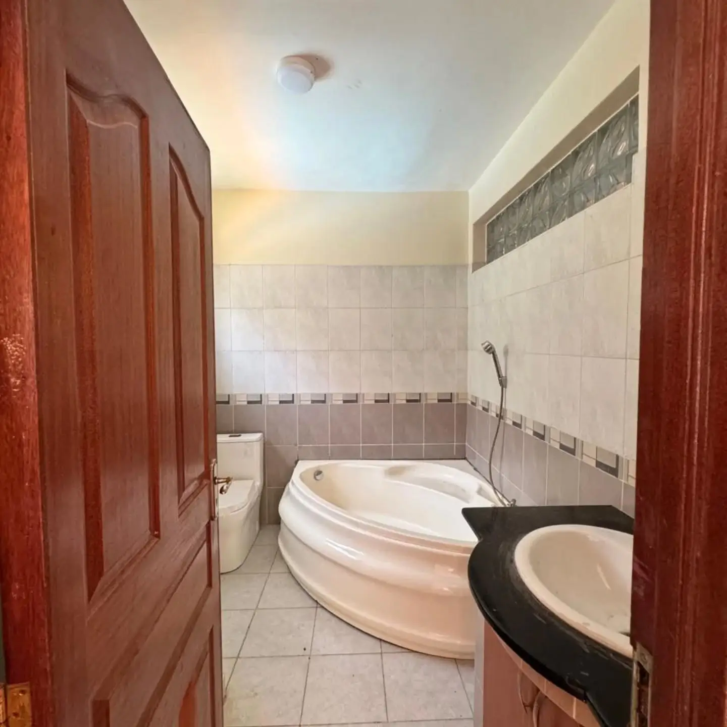 Bathroom with curved bathtub, toilet, and tiled walls.
