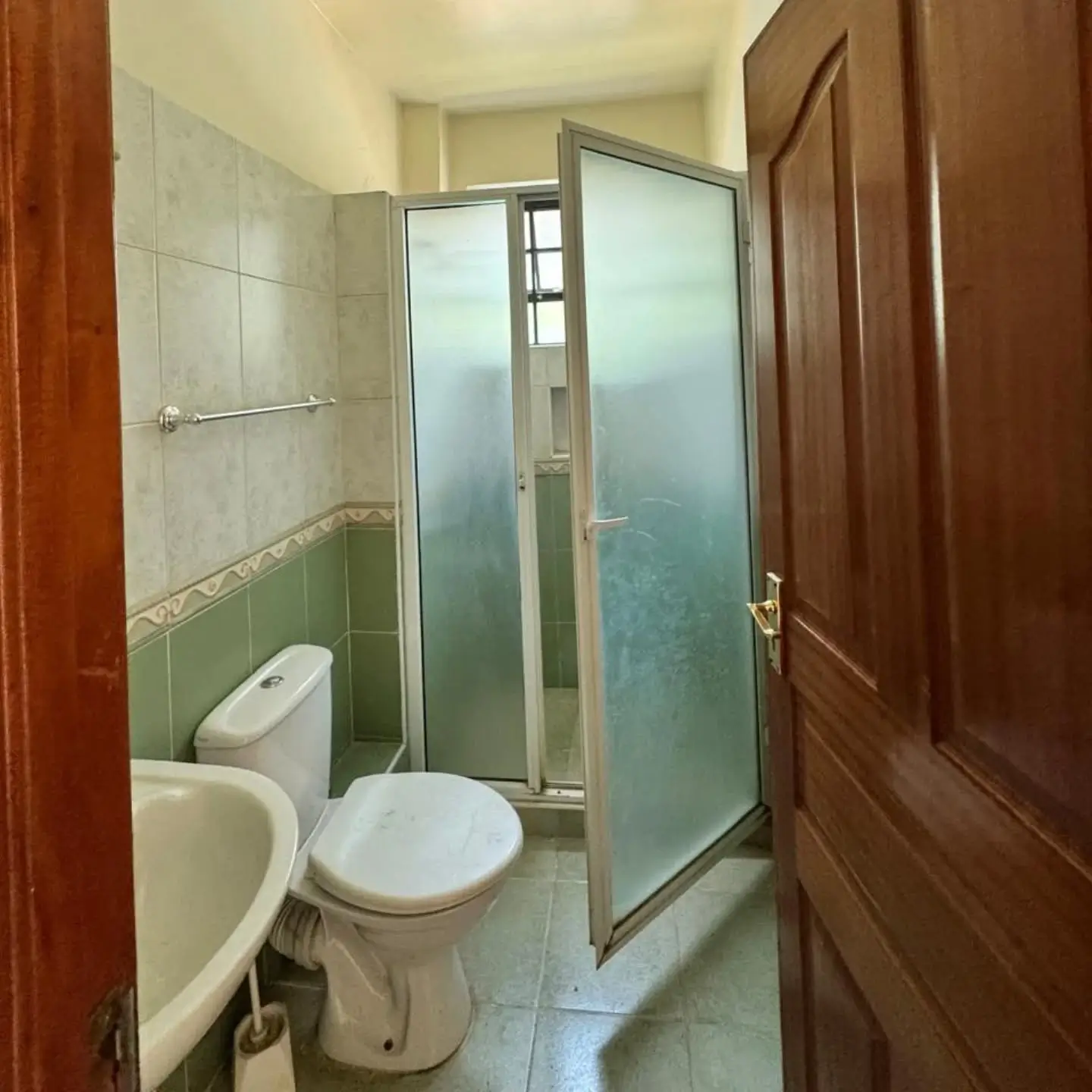 Compact bathroom with toilet, sink, shower cubicle, green tile