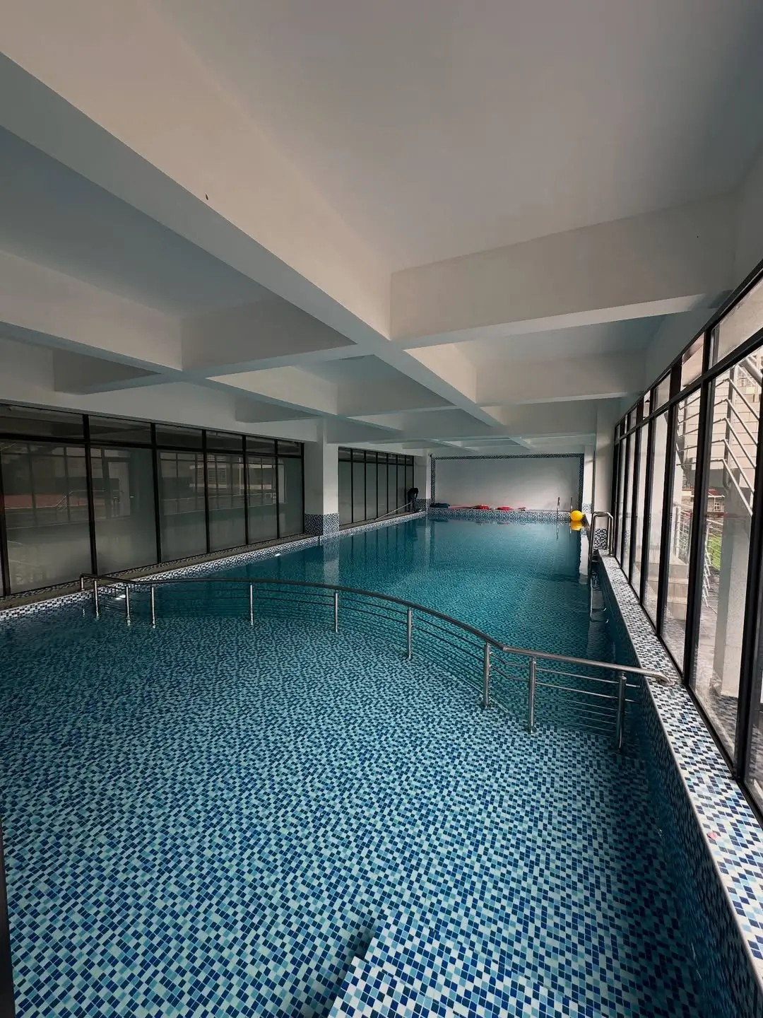Indoor swimming pool with geometric tile flooring and large windows