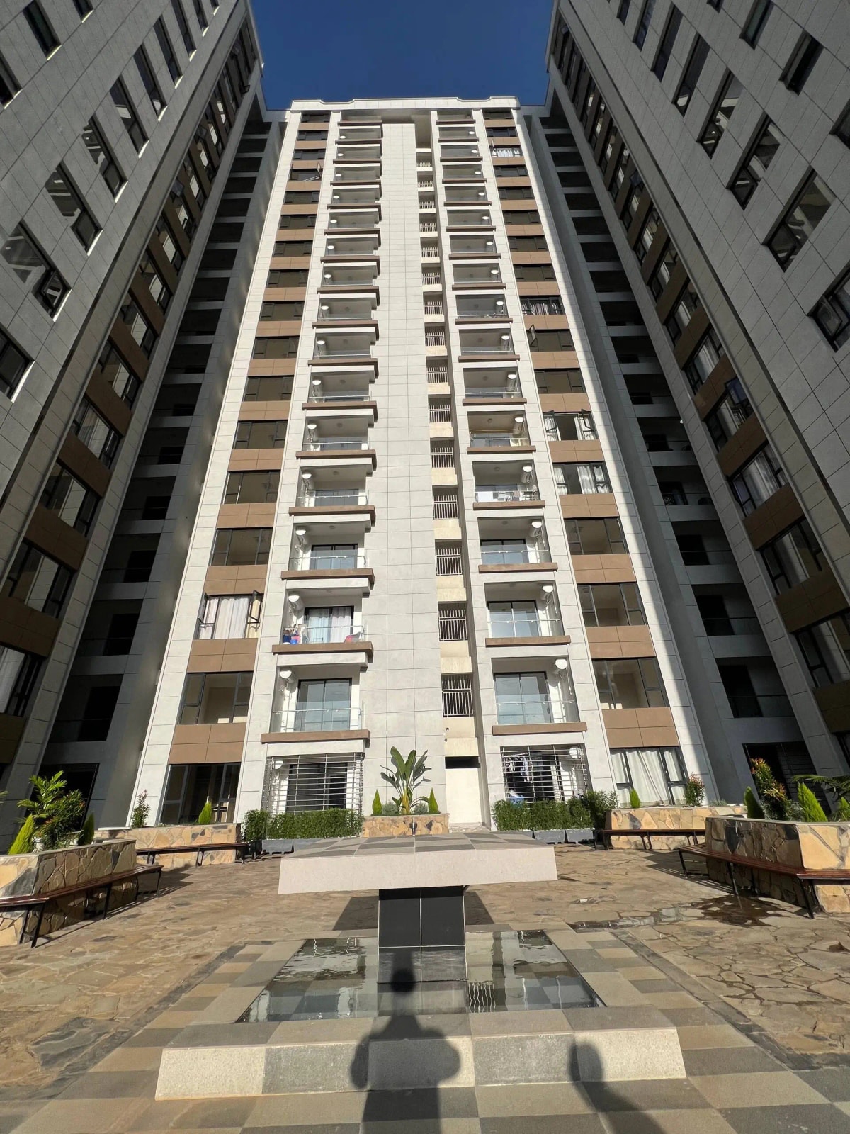 Modern multi-story residential building with landscaped compound entrance