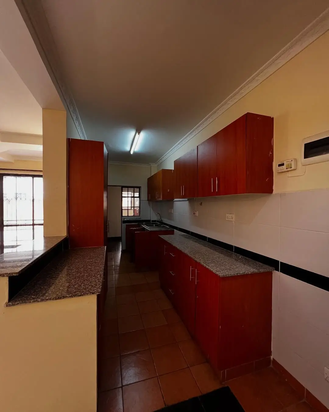 Galley kitchen with red cabinetry and granite countertops