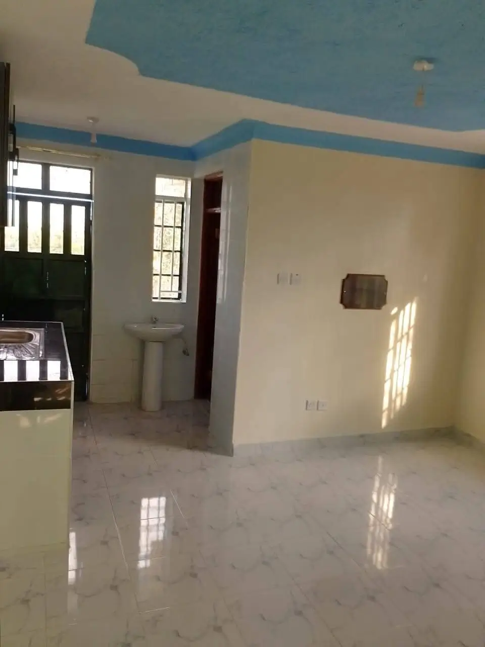 Unfurnished living space with blue accent ceiling and natural light