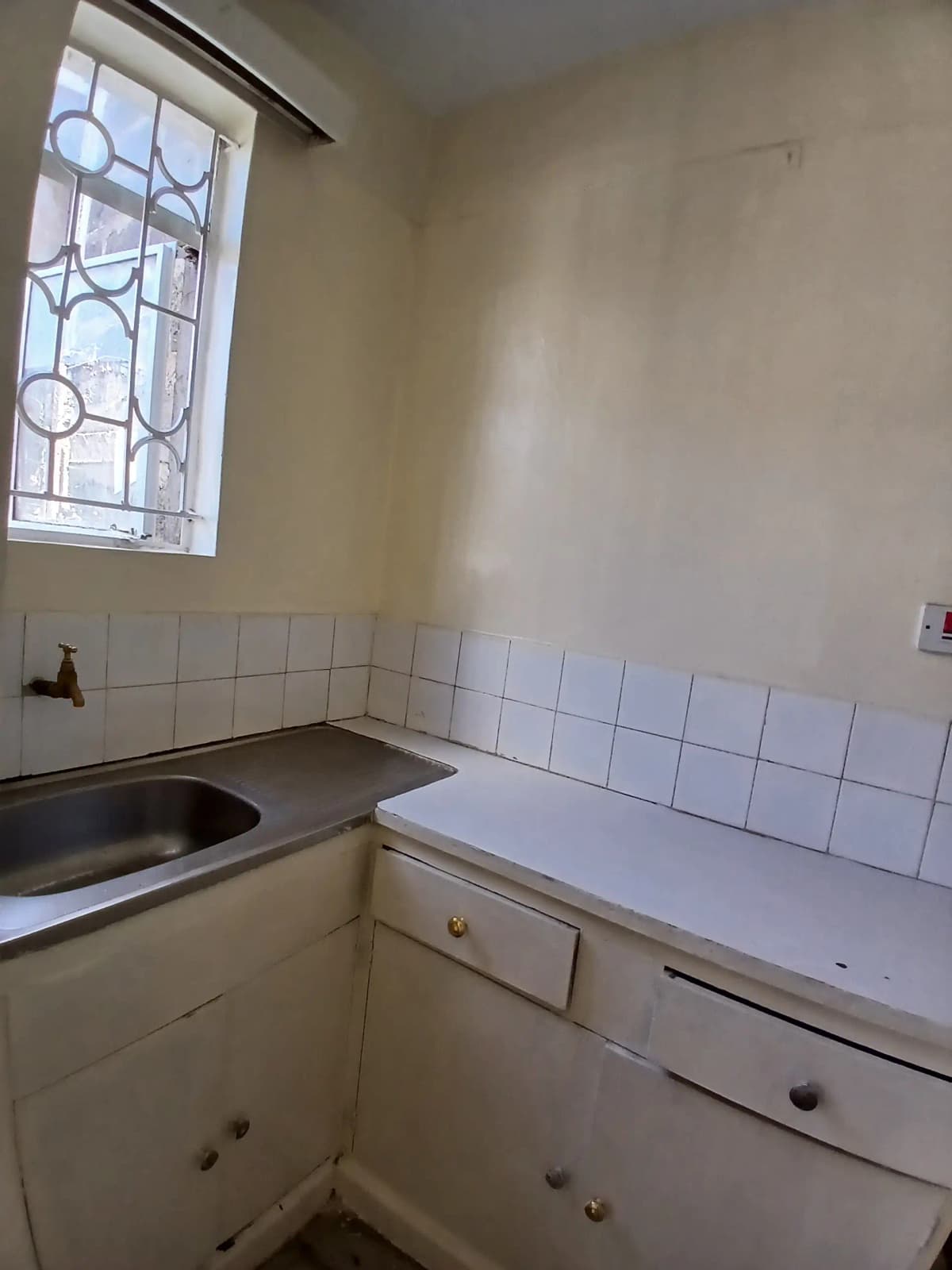Compact kitchen with sink, stove, white tile backsplash