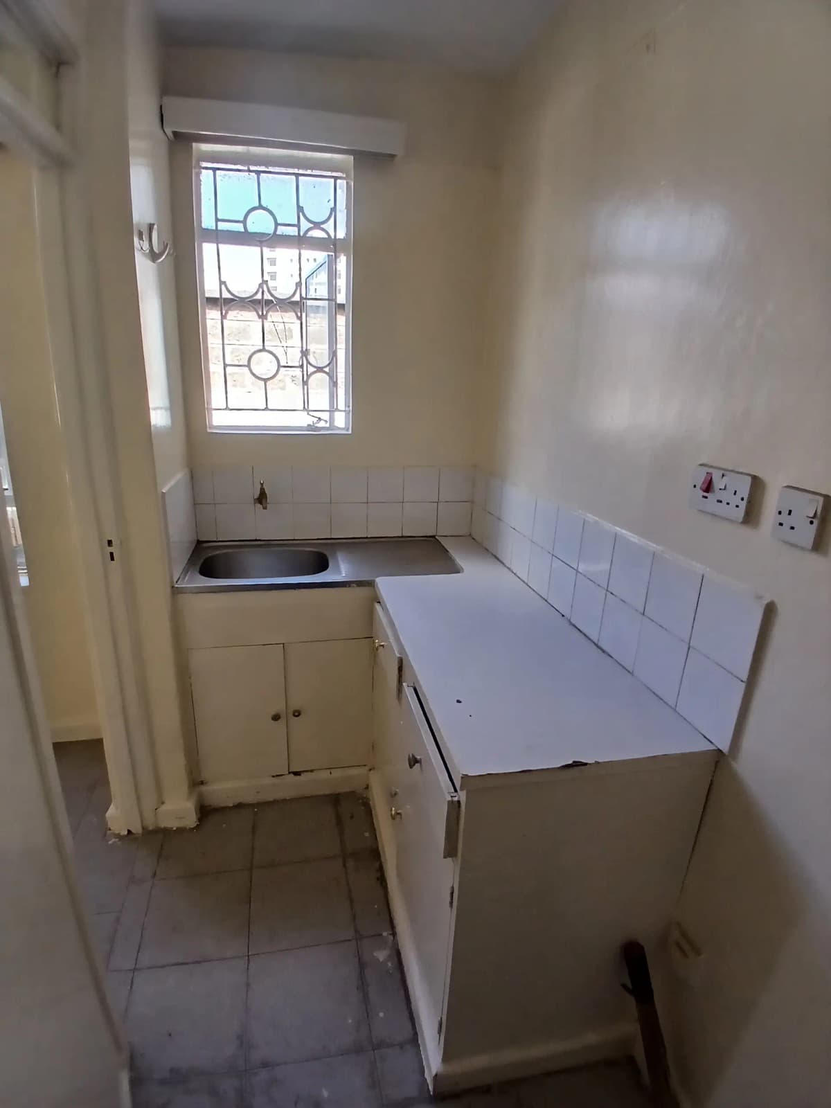 Compact galley kitchen with sink, cooker, and tile walls