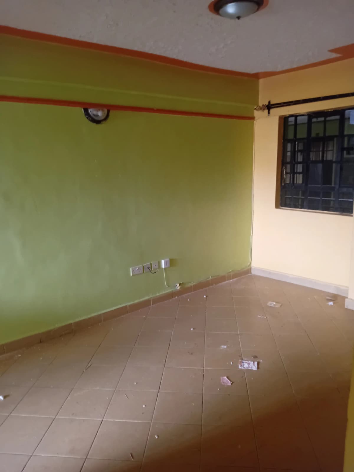 Empty living room with green accent wall and tiled flooring