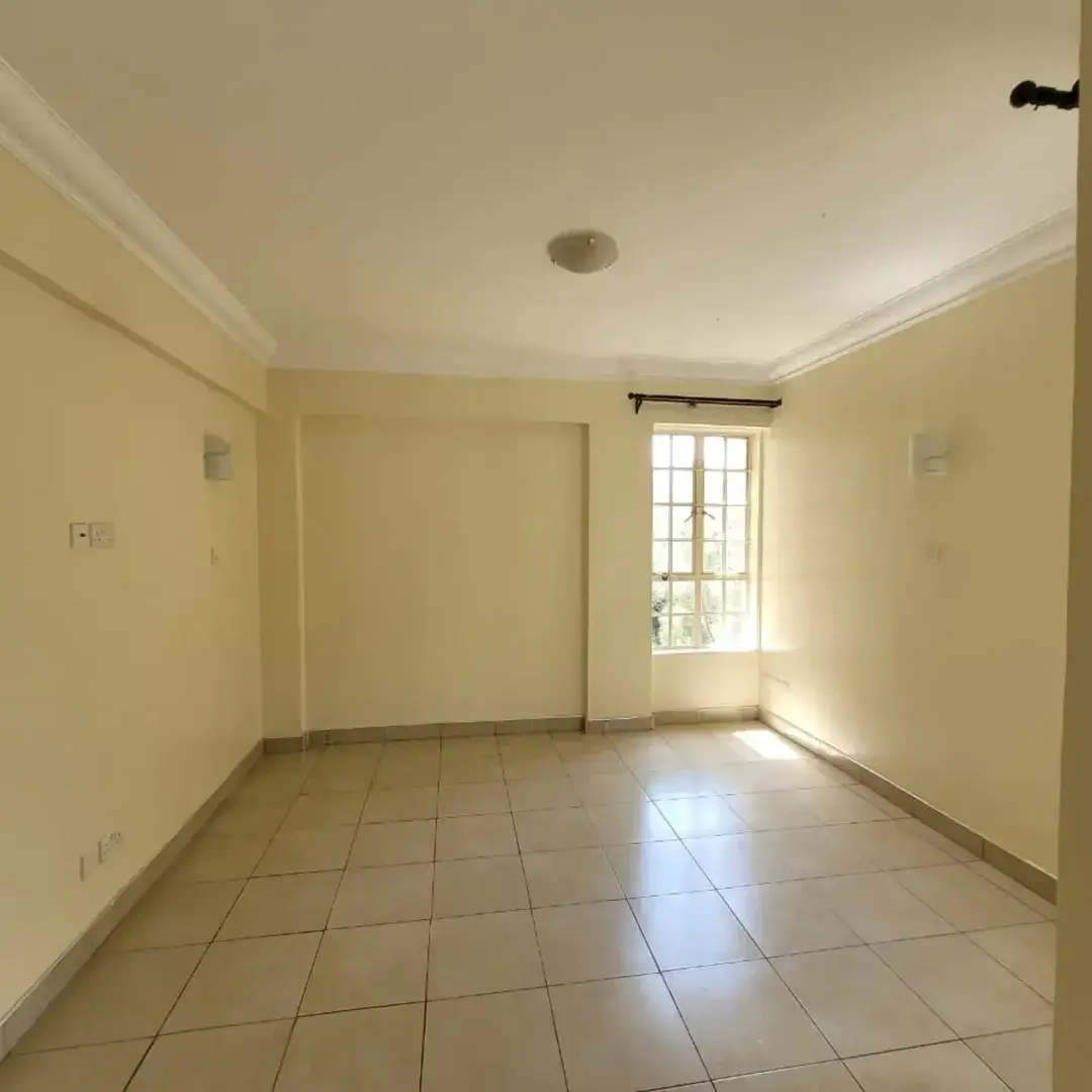 Empty living room with cream walls and tiled flooring.