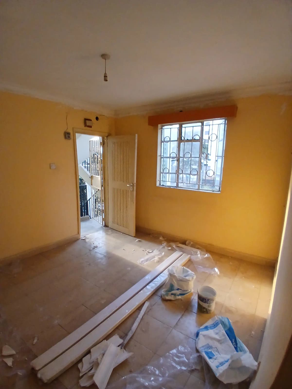 Bright yellow bedroom with large window, under renovation
