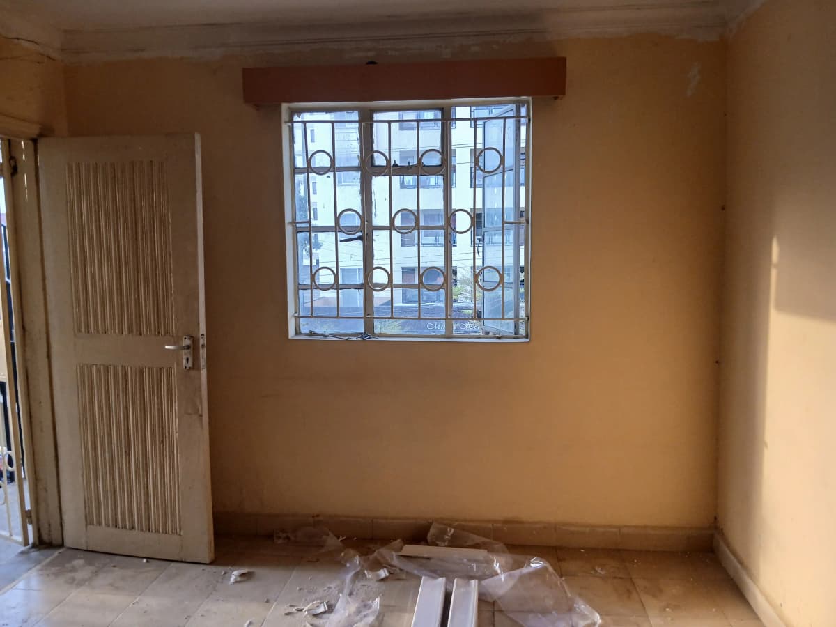 Empty bedroom with barred window and cream walls