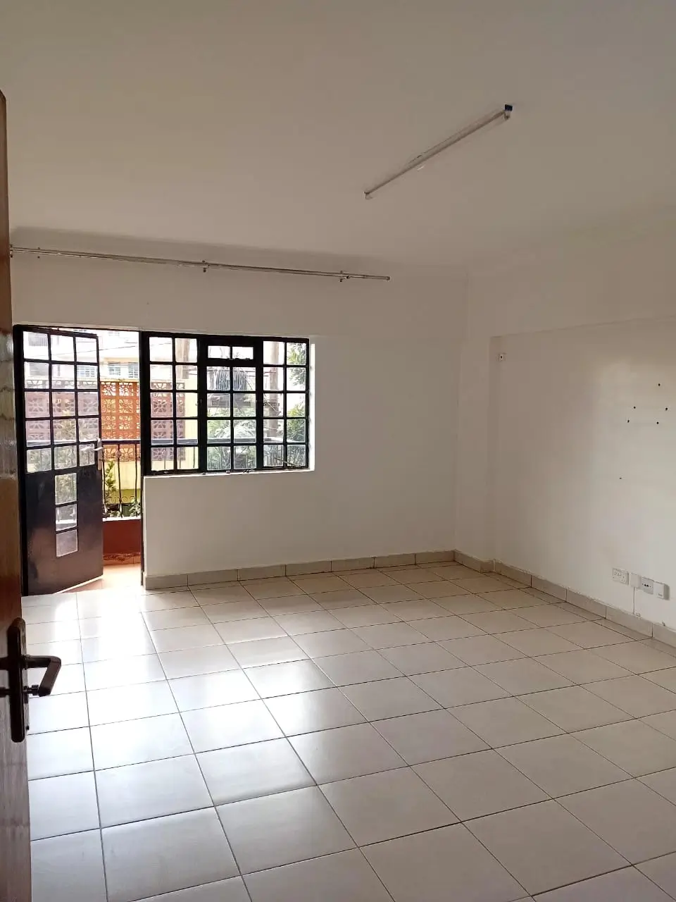 Spacious empty living room with tiled floors and large windows