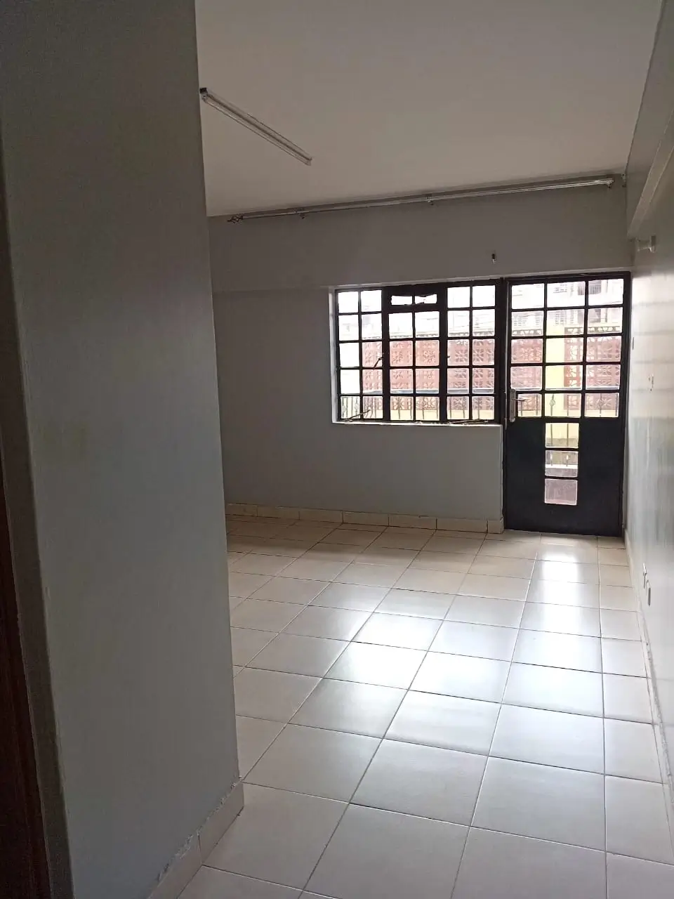 Spacious empty living room with large windows and tiled flooring
