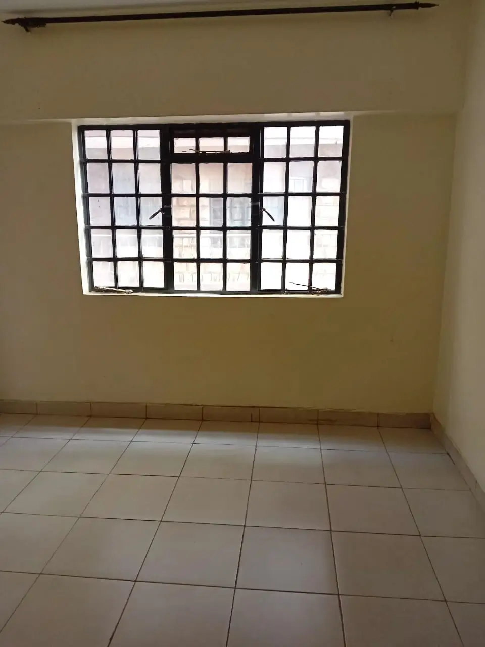 Unfurnished bedroom with barred window and tiled floor