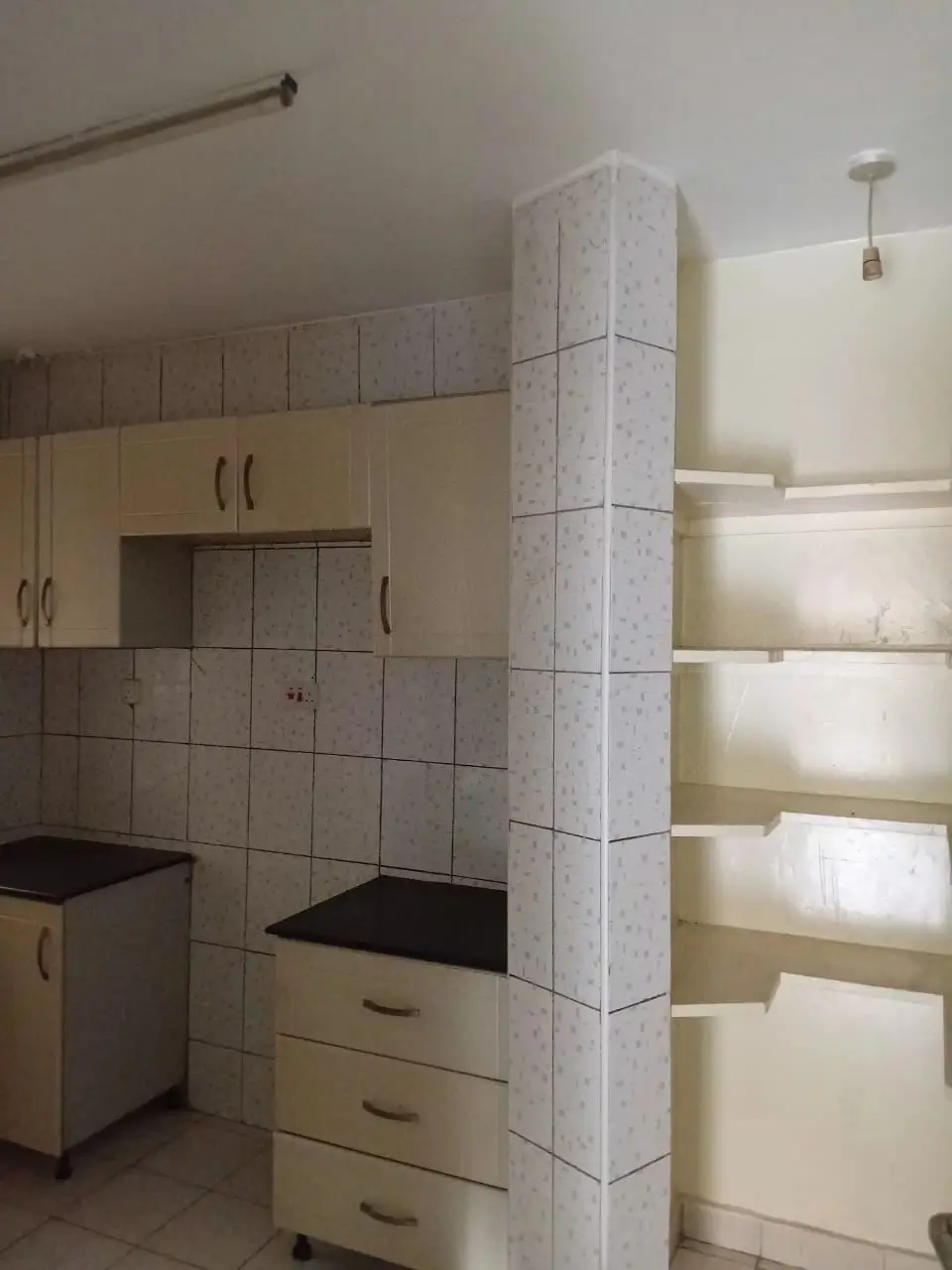 Kitchen with tiled backsplash, cream cabinets, and open shelving