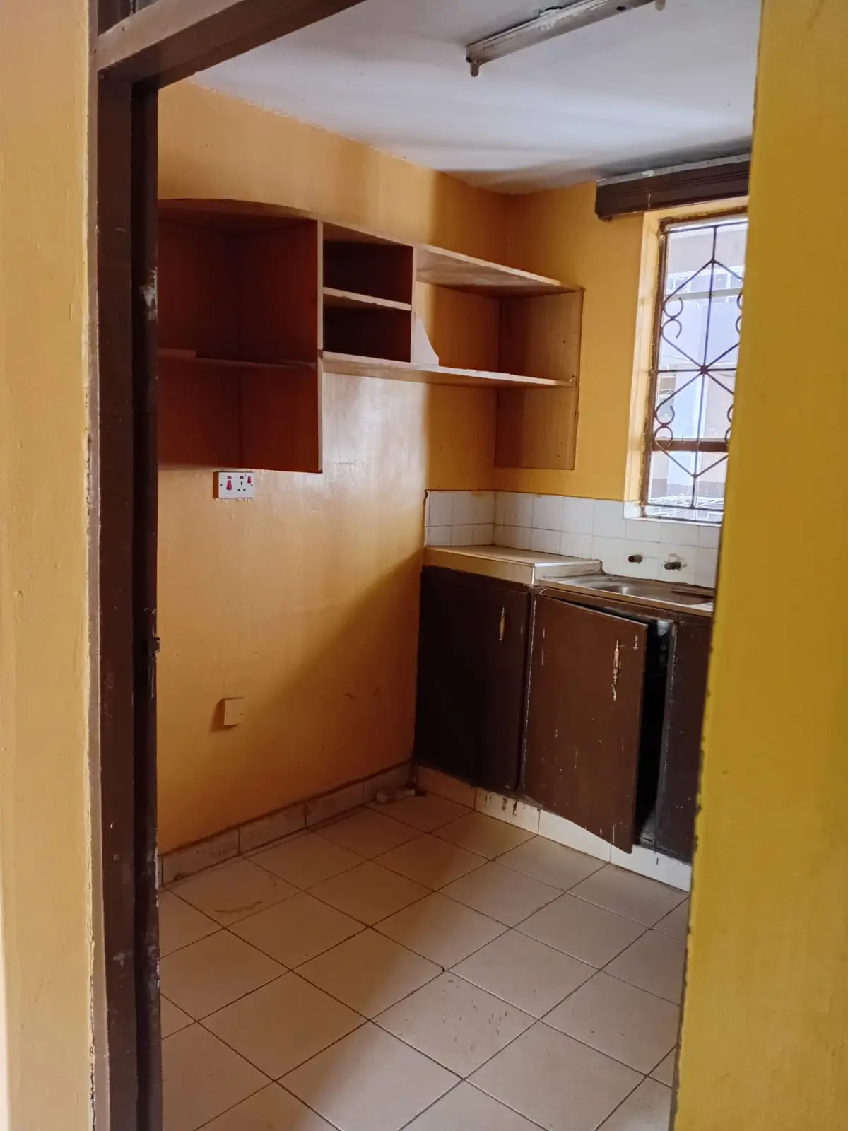 Compact kitchen with wooden cabinetry and tile flooring