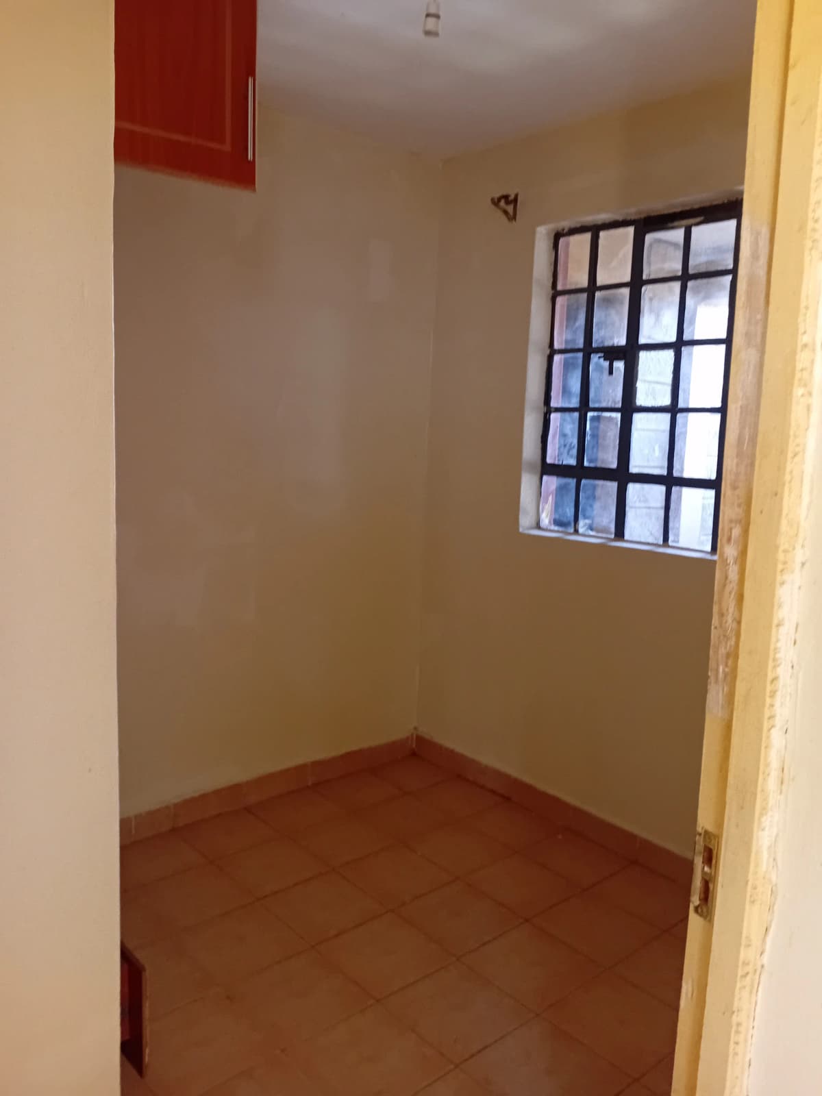 Compact bedroom with terracotta floor and barred window