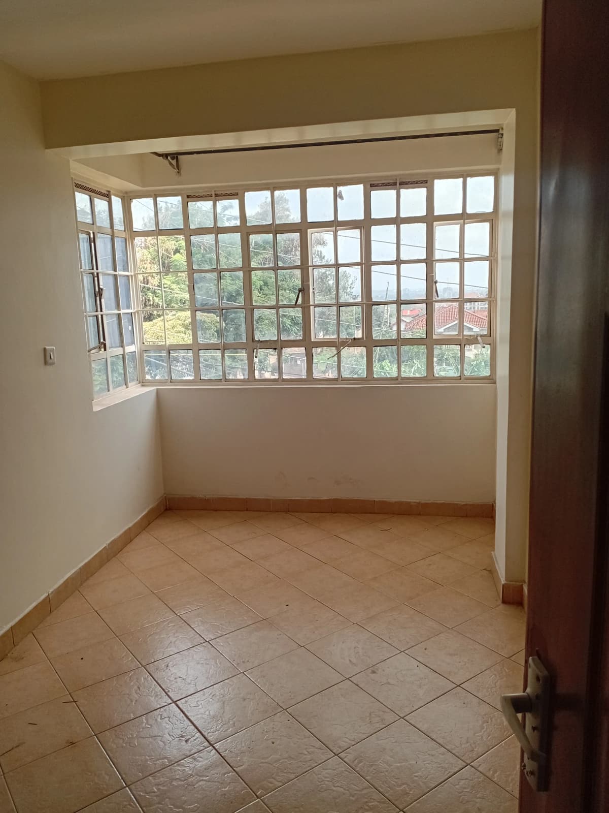 Bright bedroom with large gridded window and terracotta tile floor