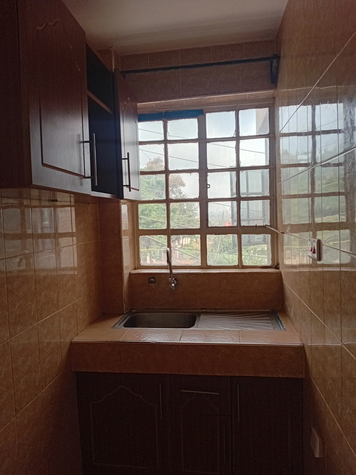 Kitchen with wooden cabinets and large window overlooking grounds