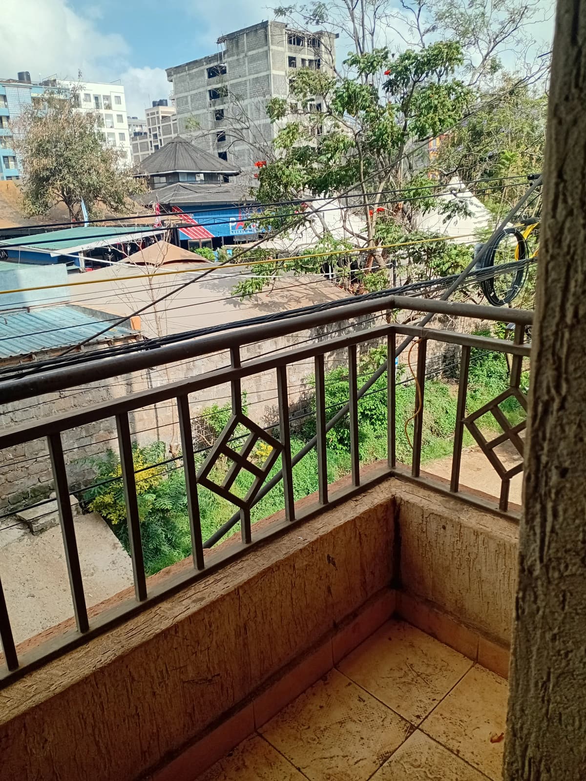Balcony with metal railing overlooking compound and city buildings