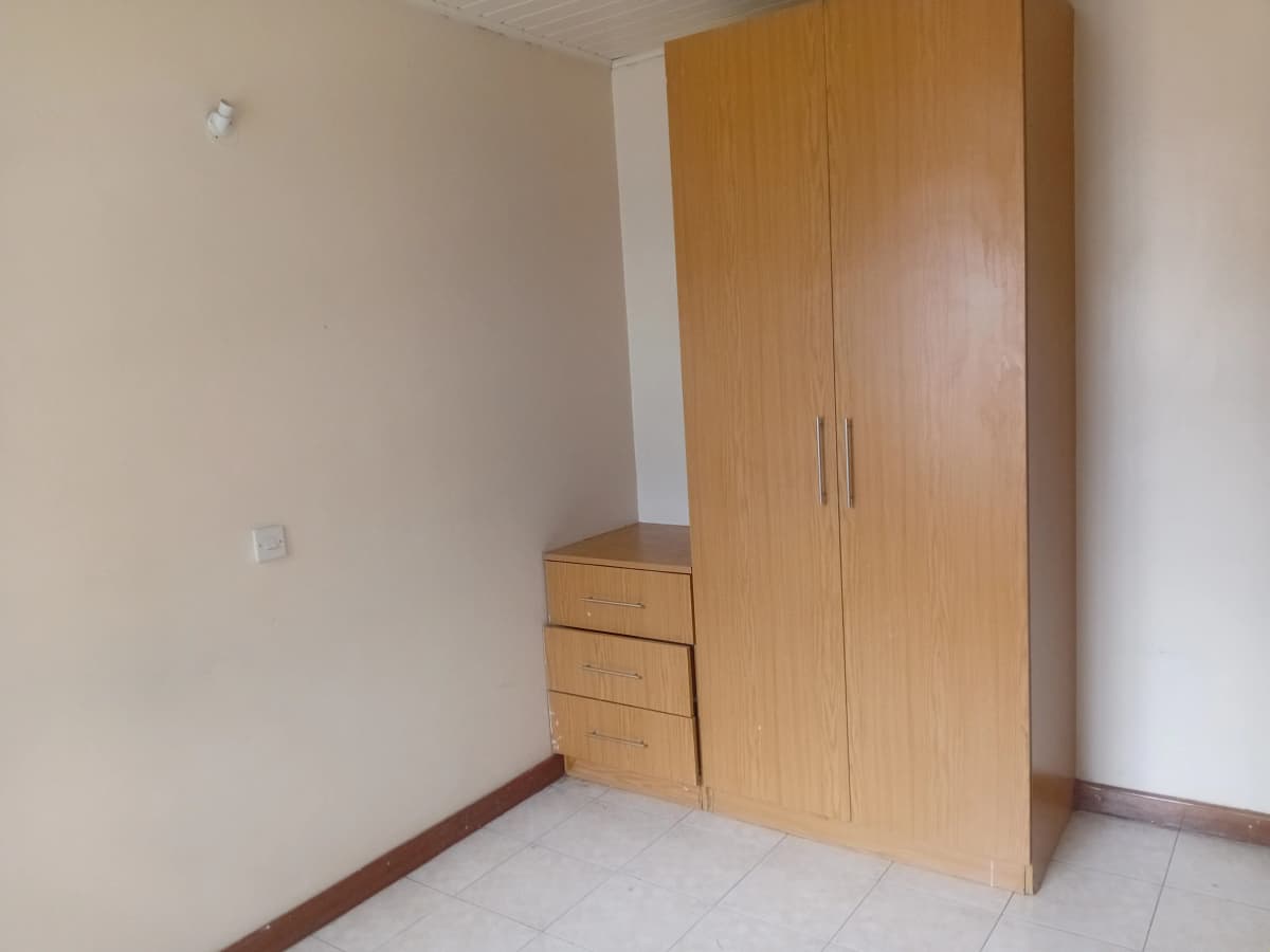 Empty bedroom with built-in wooden wardrobe and drawers