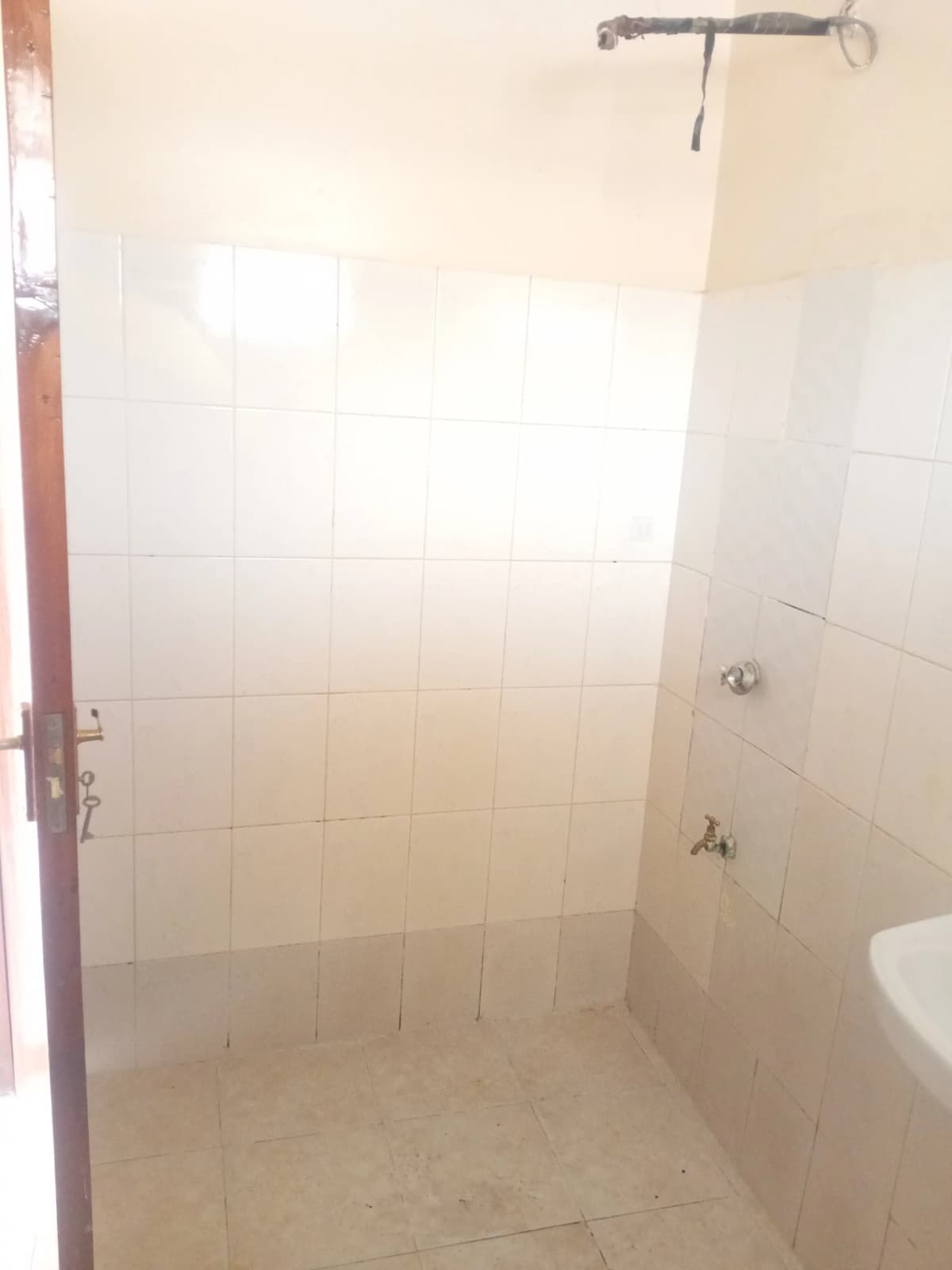 Simple bathroom with white tile walls and shower fixture