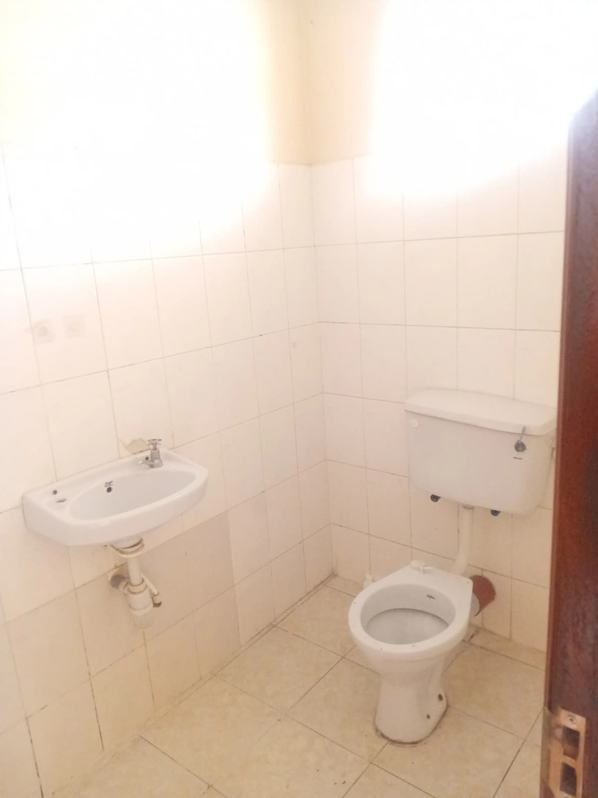 Simple bathroom with toilet, sink, and tiled walls