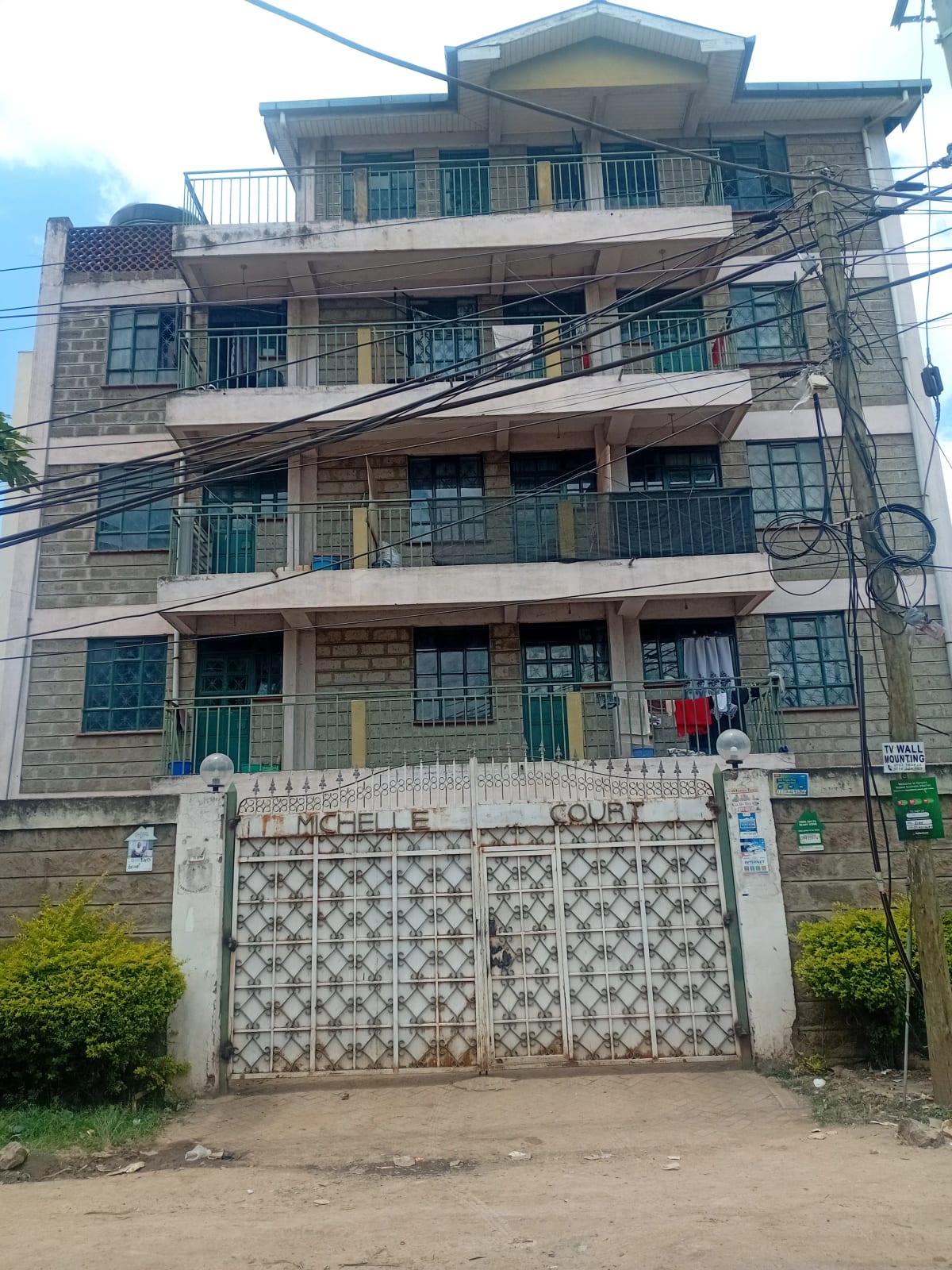 Four-story residential building with balconies and gated entrance