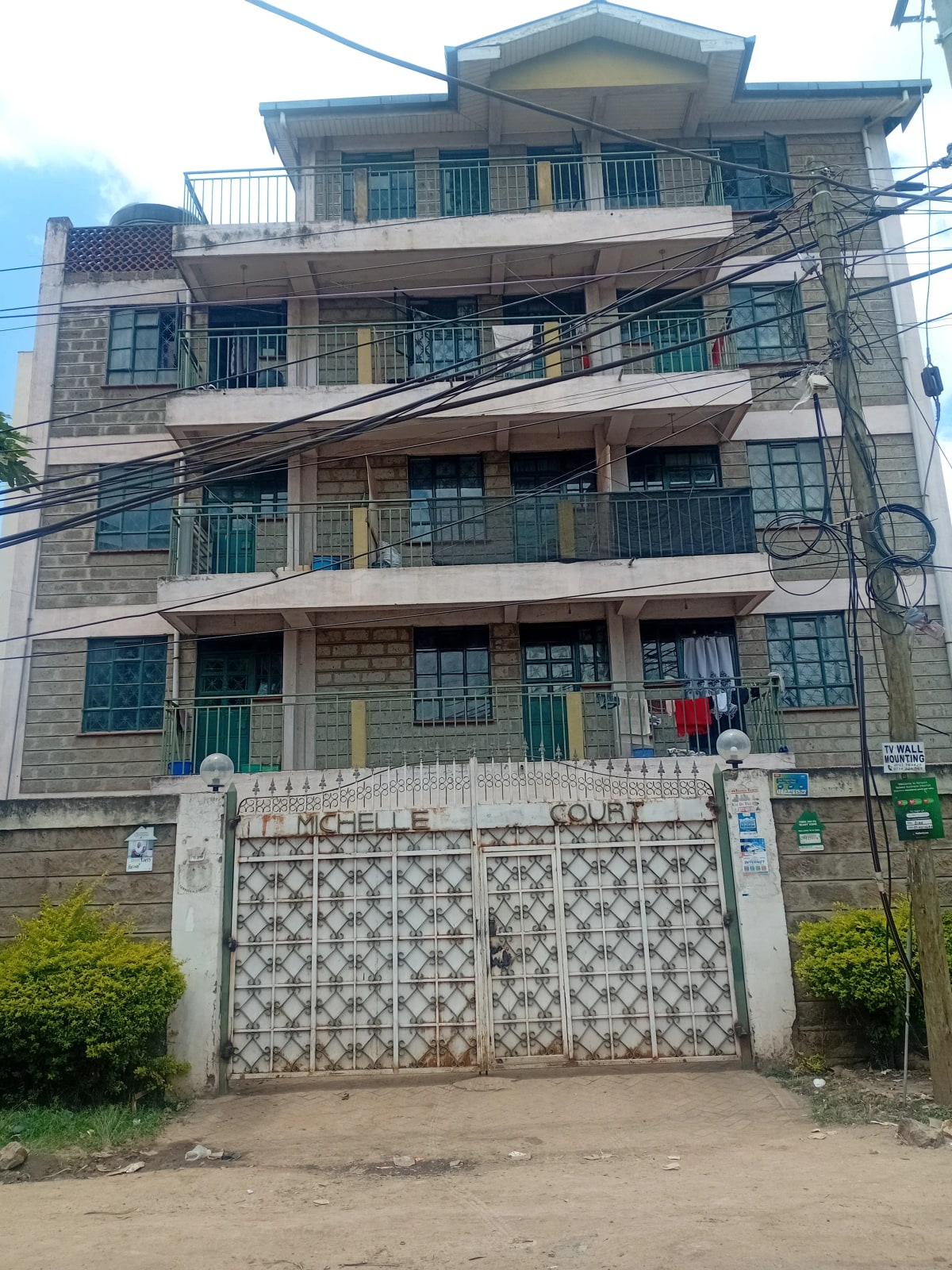 Four-story residential building with balconies and gated entrance