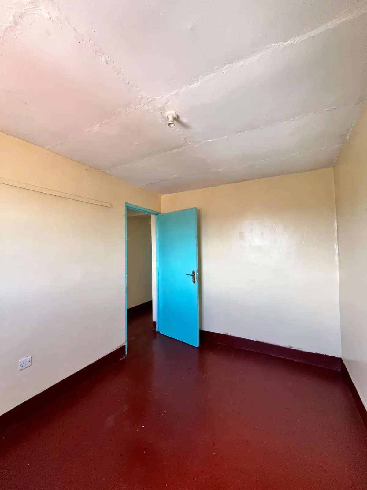 Unfurnished bedroom with burgundy floor and blue door