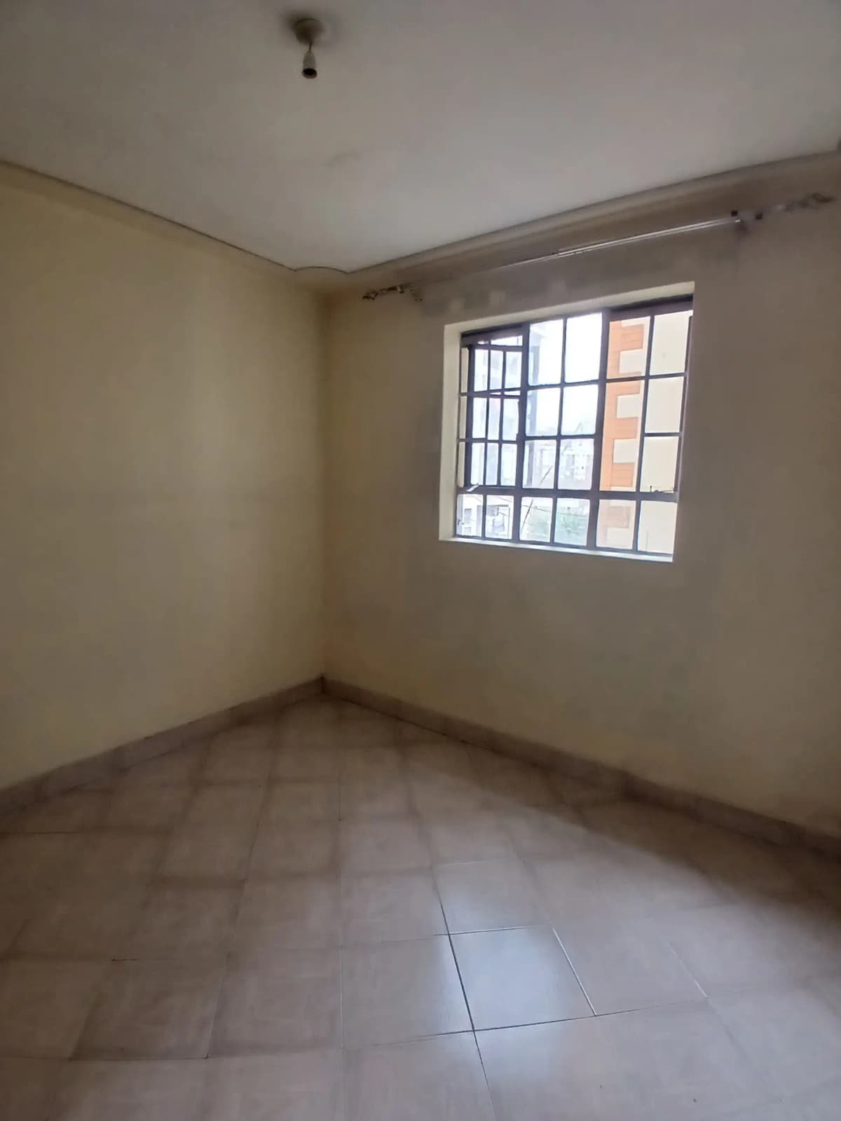 Empty bedroom with tiled floor and barred window