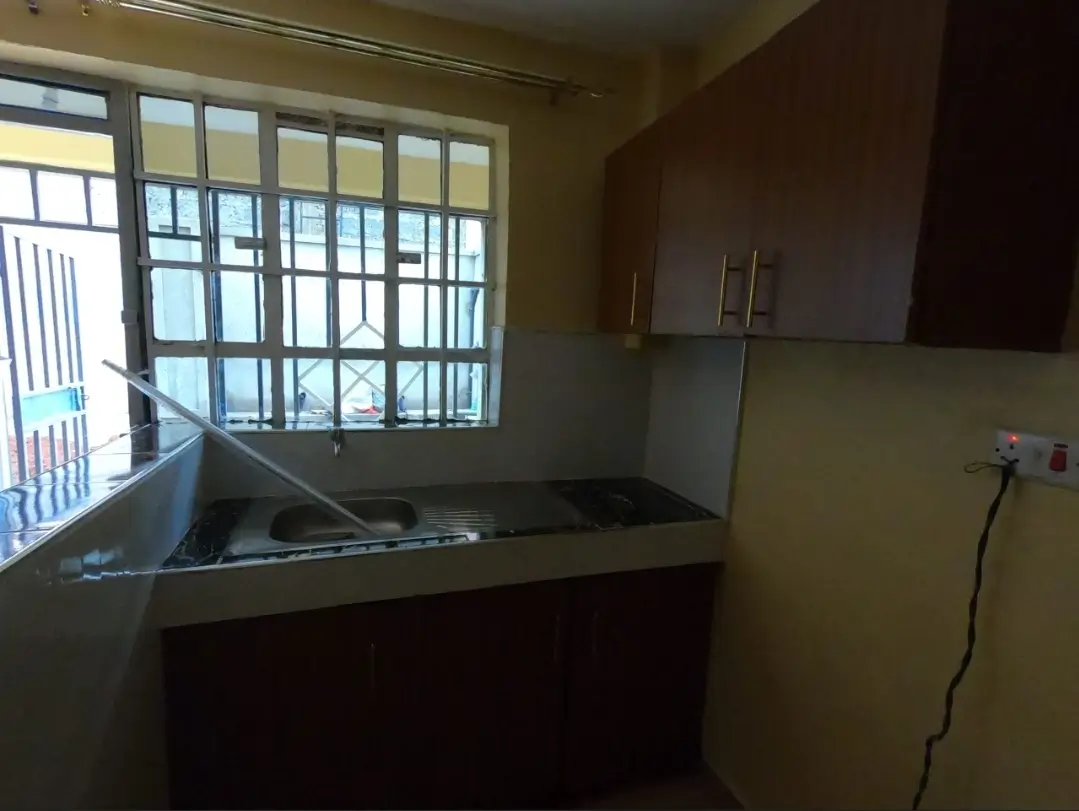 Compact kitchen with dark cabinetry and barred window