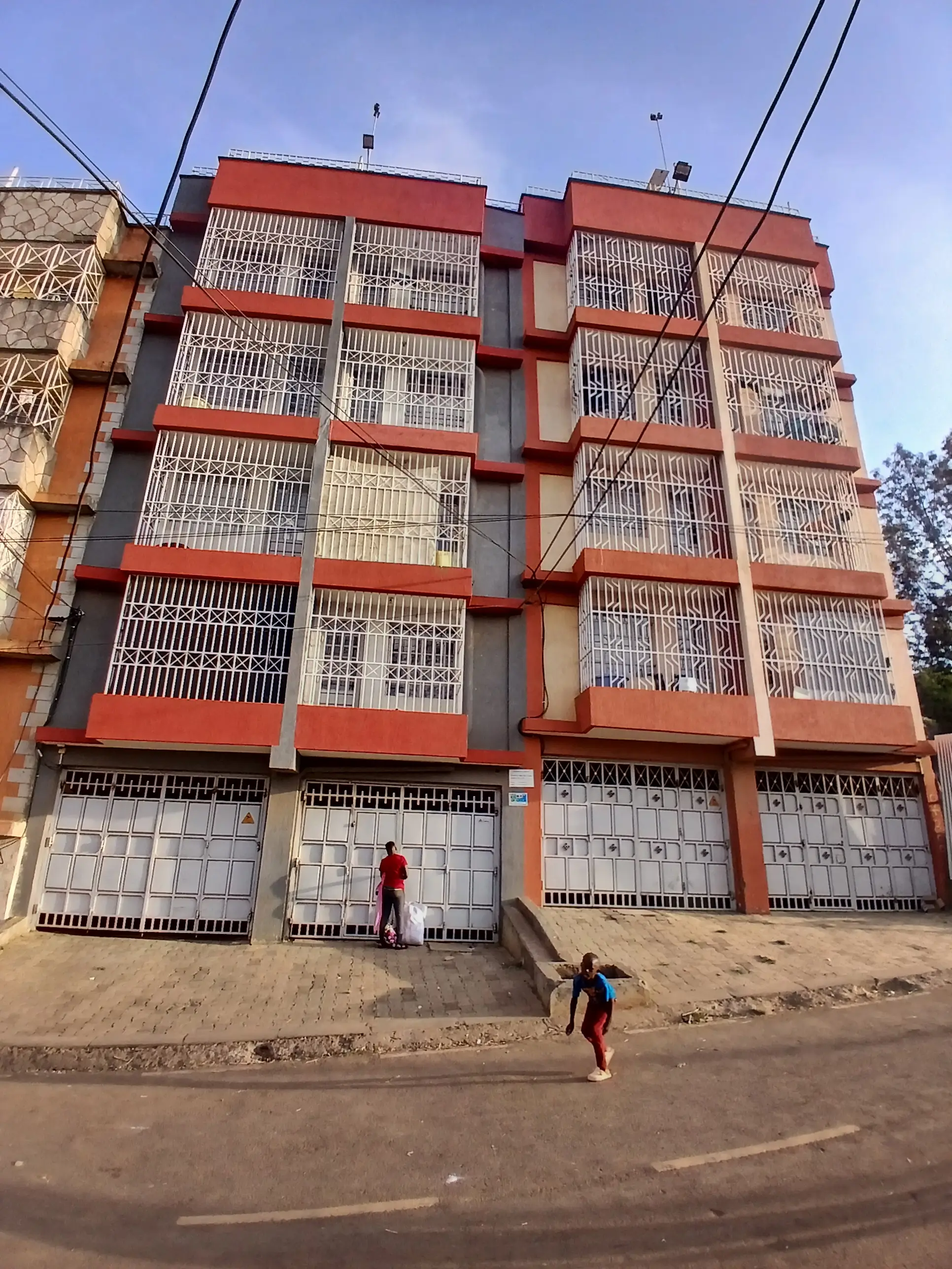 Multi-story residential building facade with red trim and garages