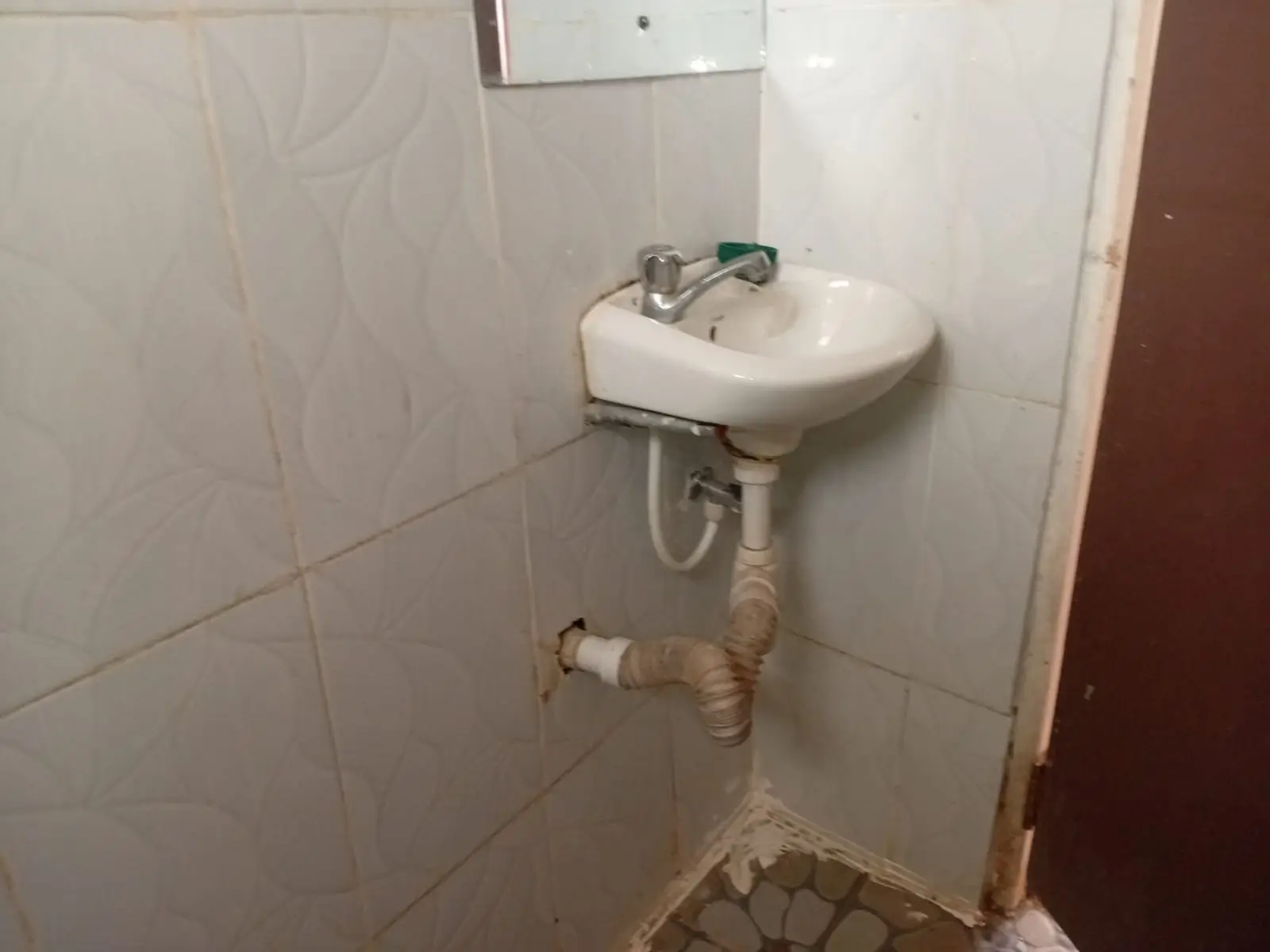 Compact bathroom with wall-mounted sink and exposed plumbing