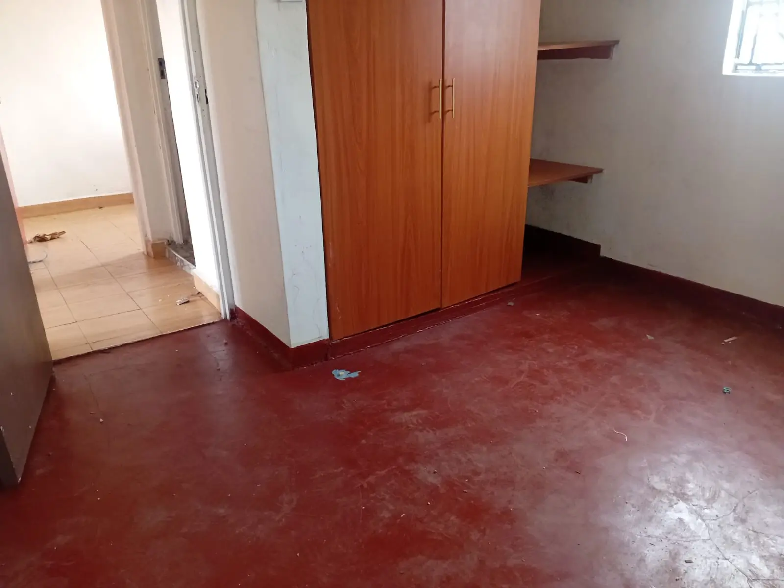 Spacious bedroom with wooden wardrobe and red concrete flooring
