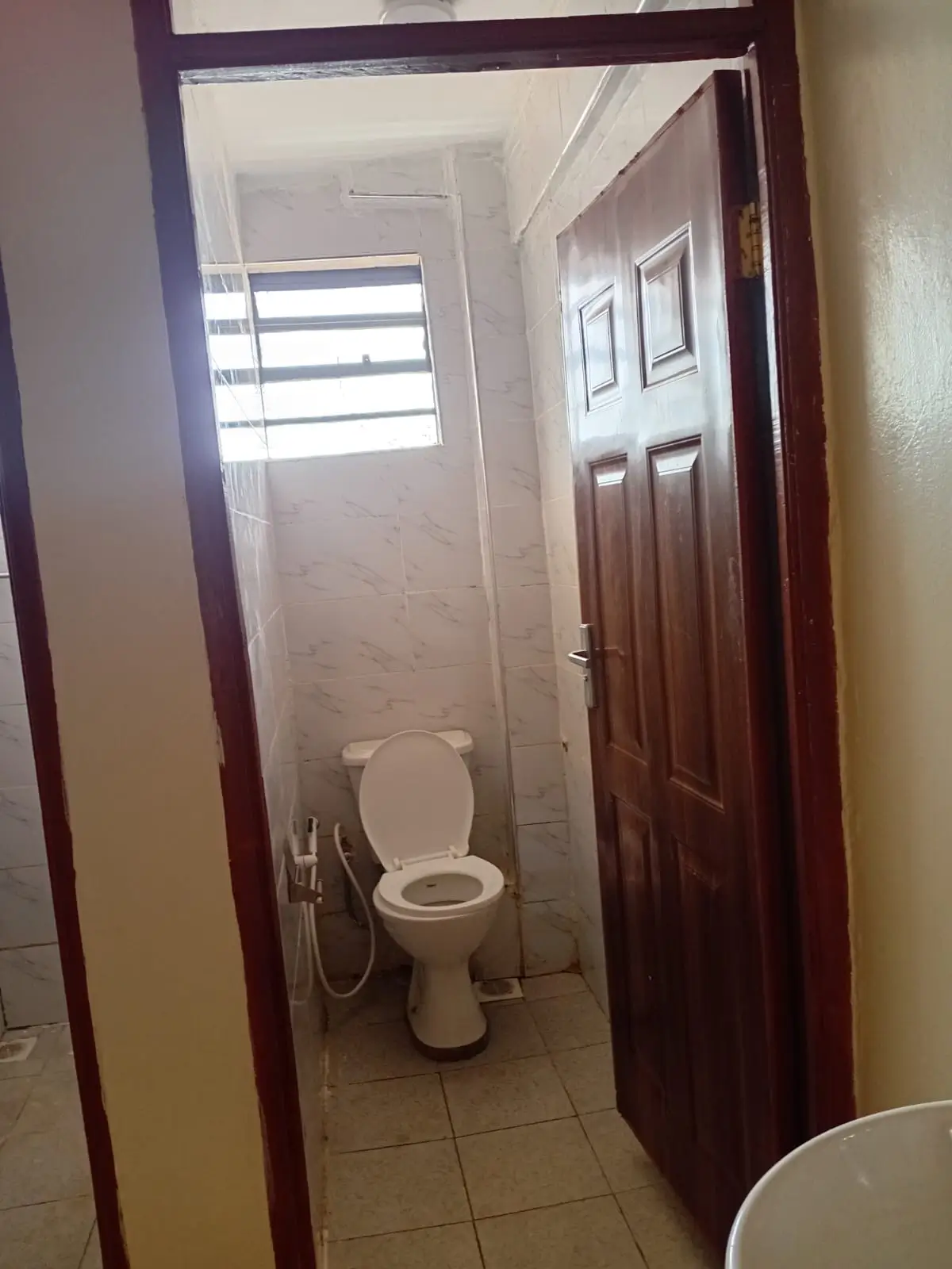 Compact bathroom with toilet and high window for ventilation