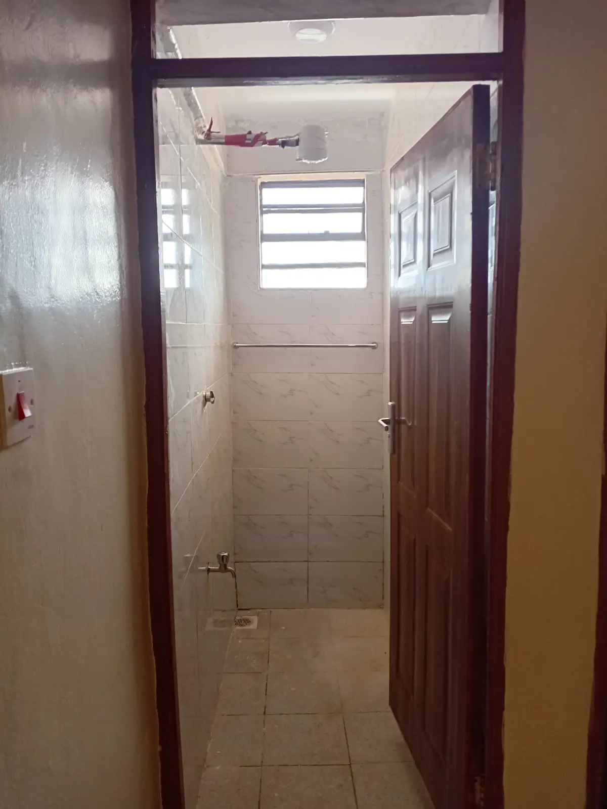 Narrow bathroom with tiled walls and frosted window