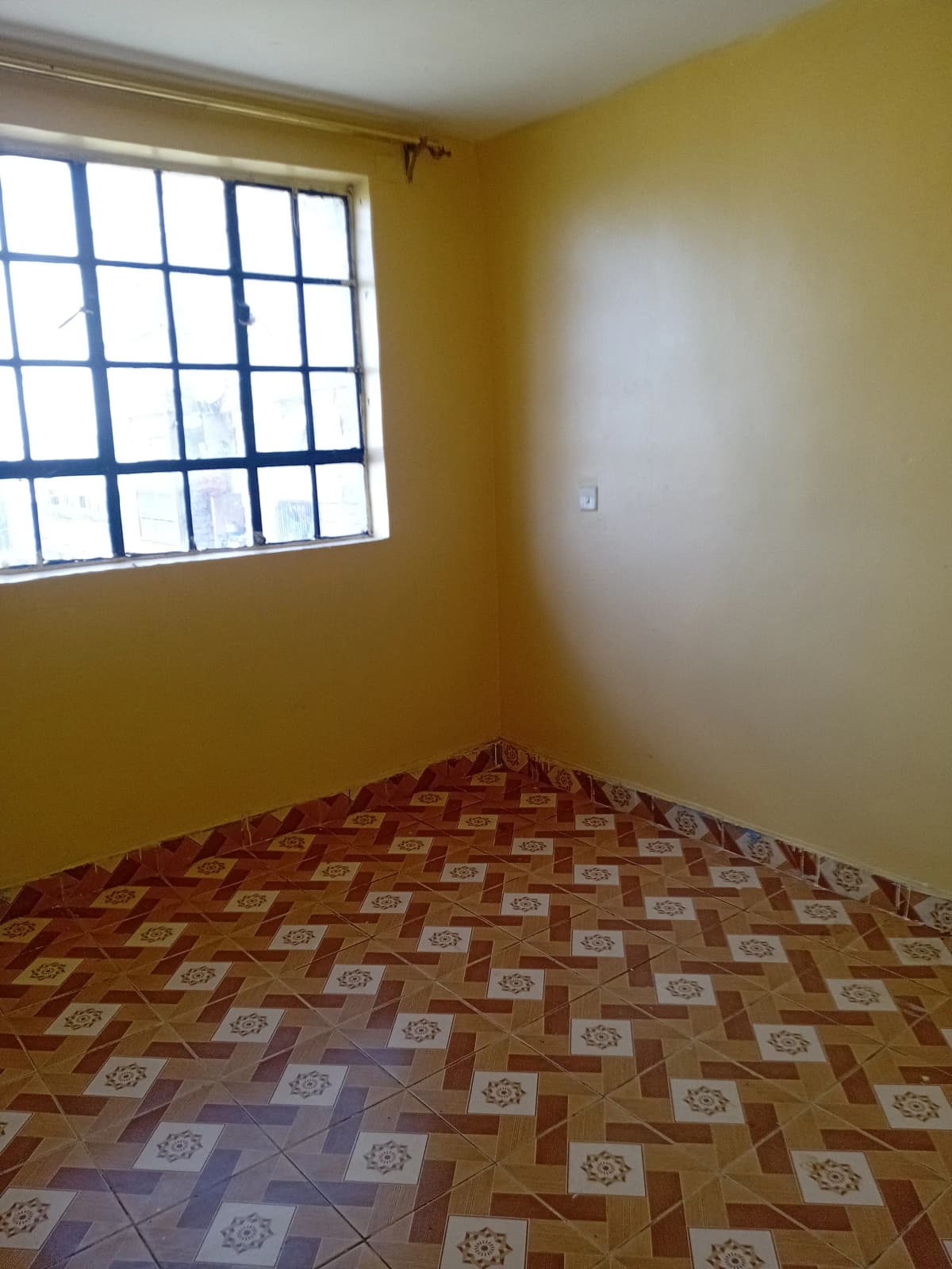 Bright bedroom with geometric tile floor and barred window