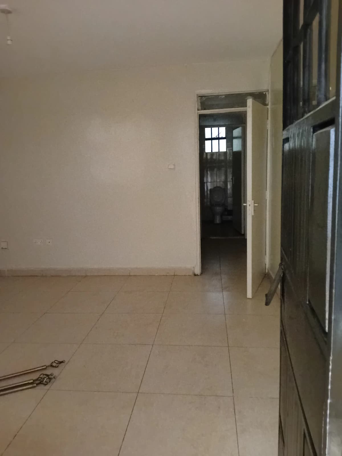 Empty living room with tiled flooring and white walls