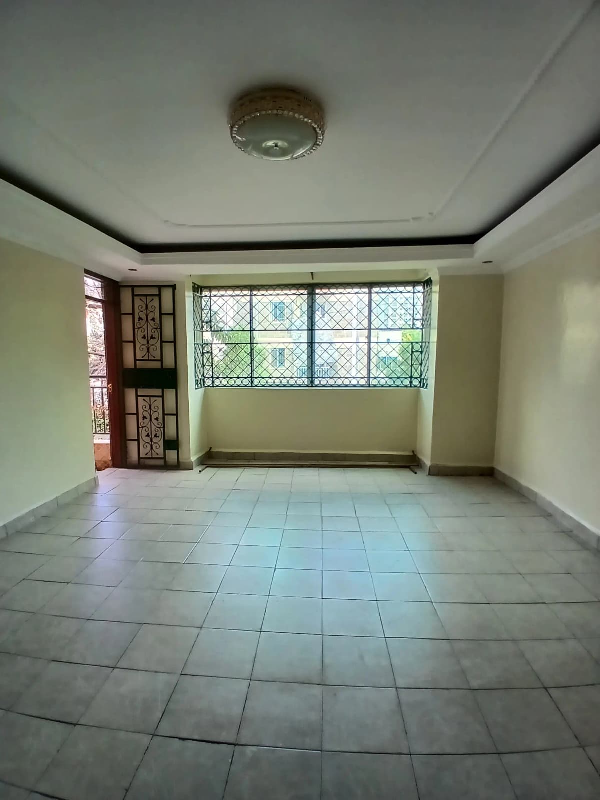 Spacious living room with large windows and tiled flooring