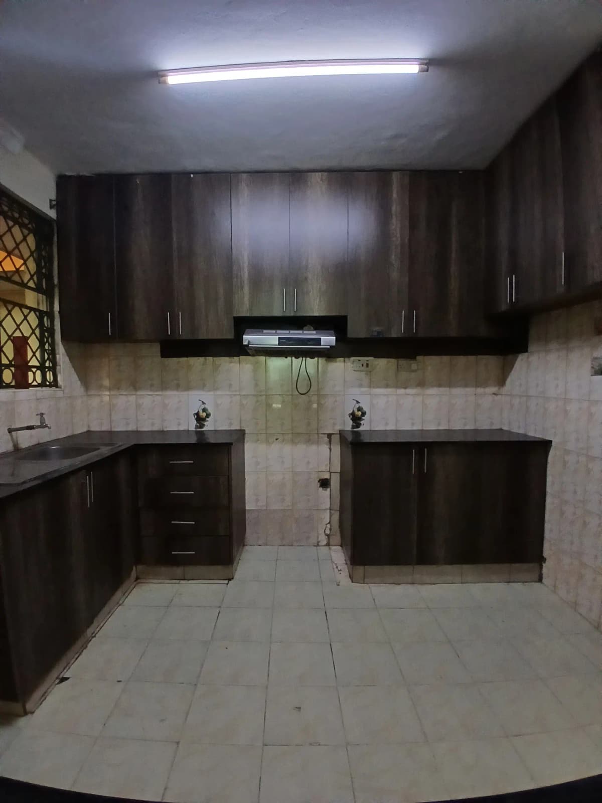 Modern kitchen with dark cabinetry and light tile flooring