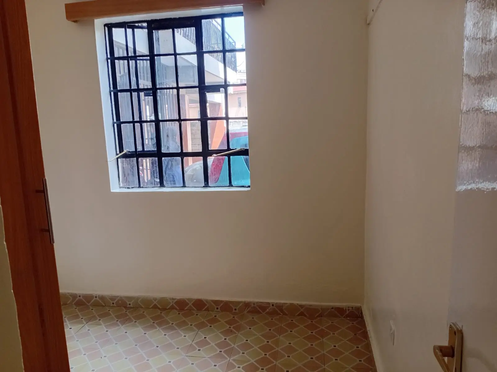Unfurnished bedroom with barred window and terracotta tile floor