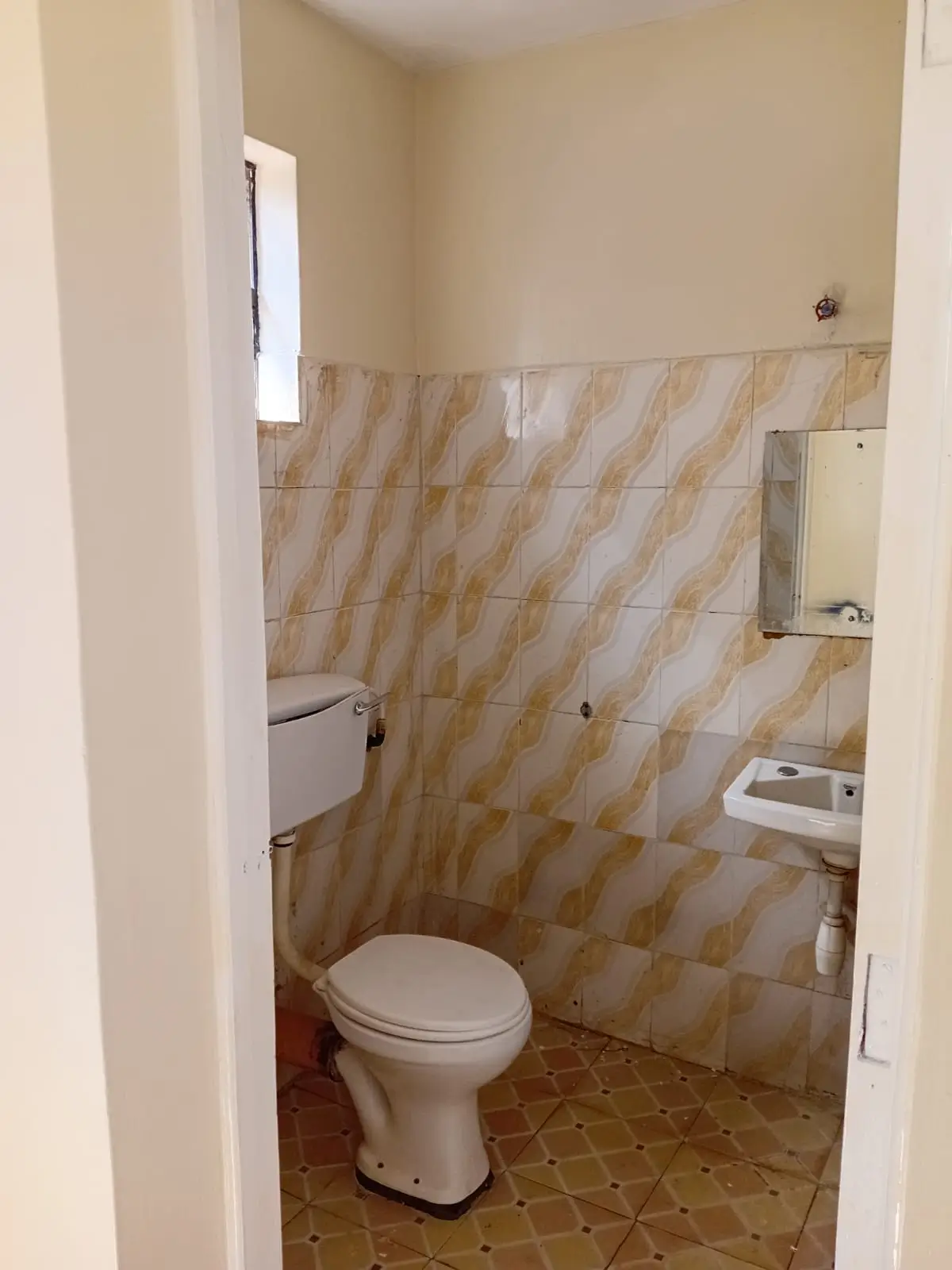 Compact bathroom with toilet, sink, and geometric tile walls