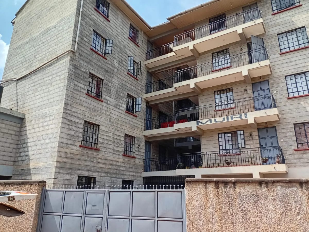 Multi-story residential building with balconies and metal gate