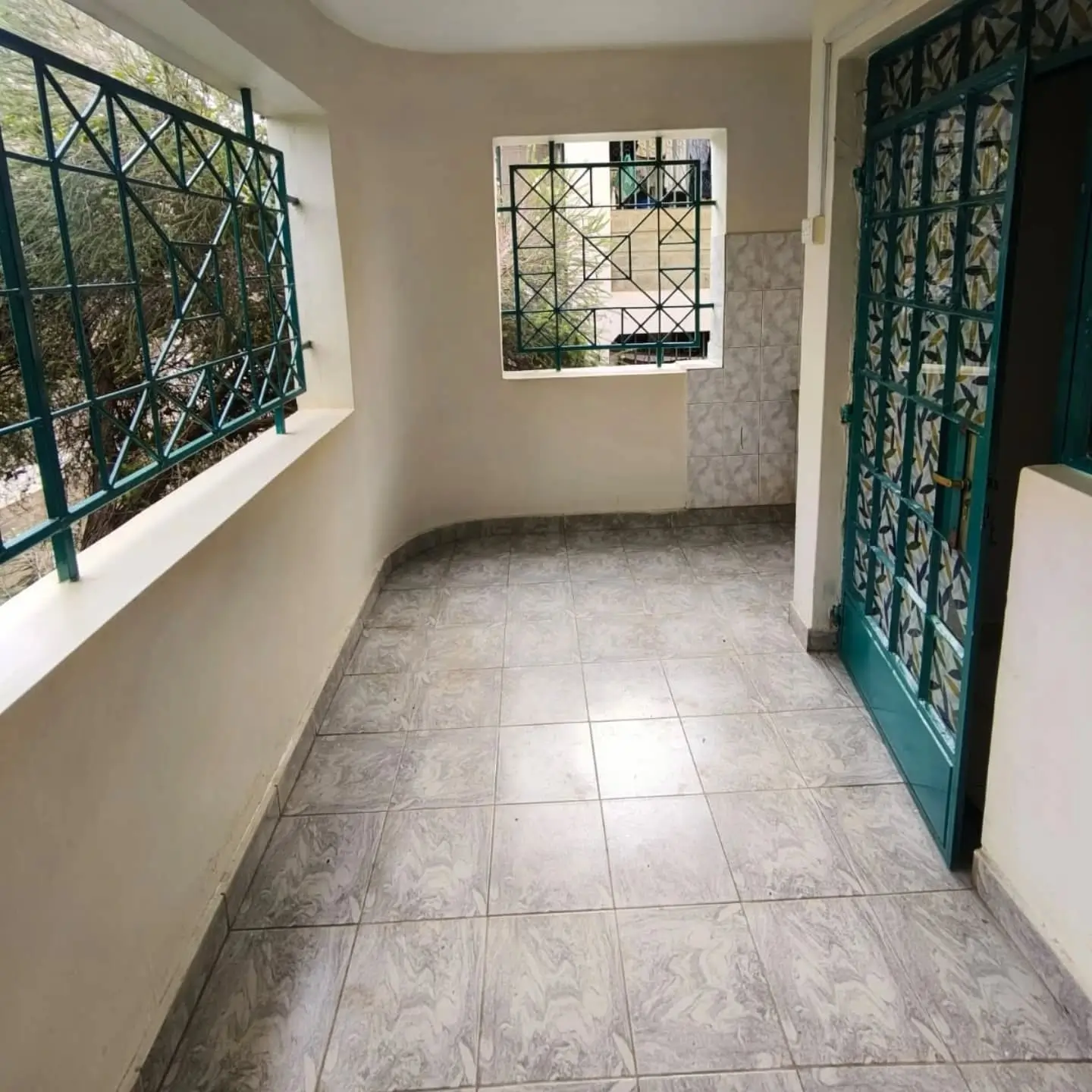 Covered balcony with tiled floor and green metal railings